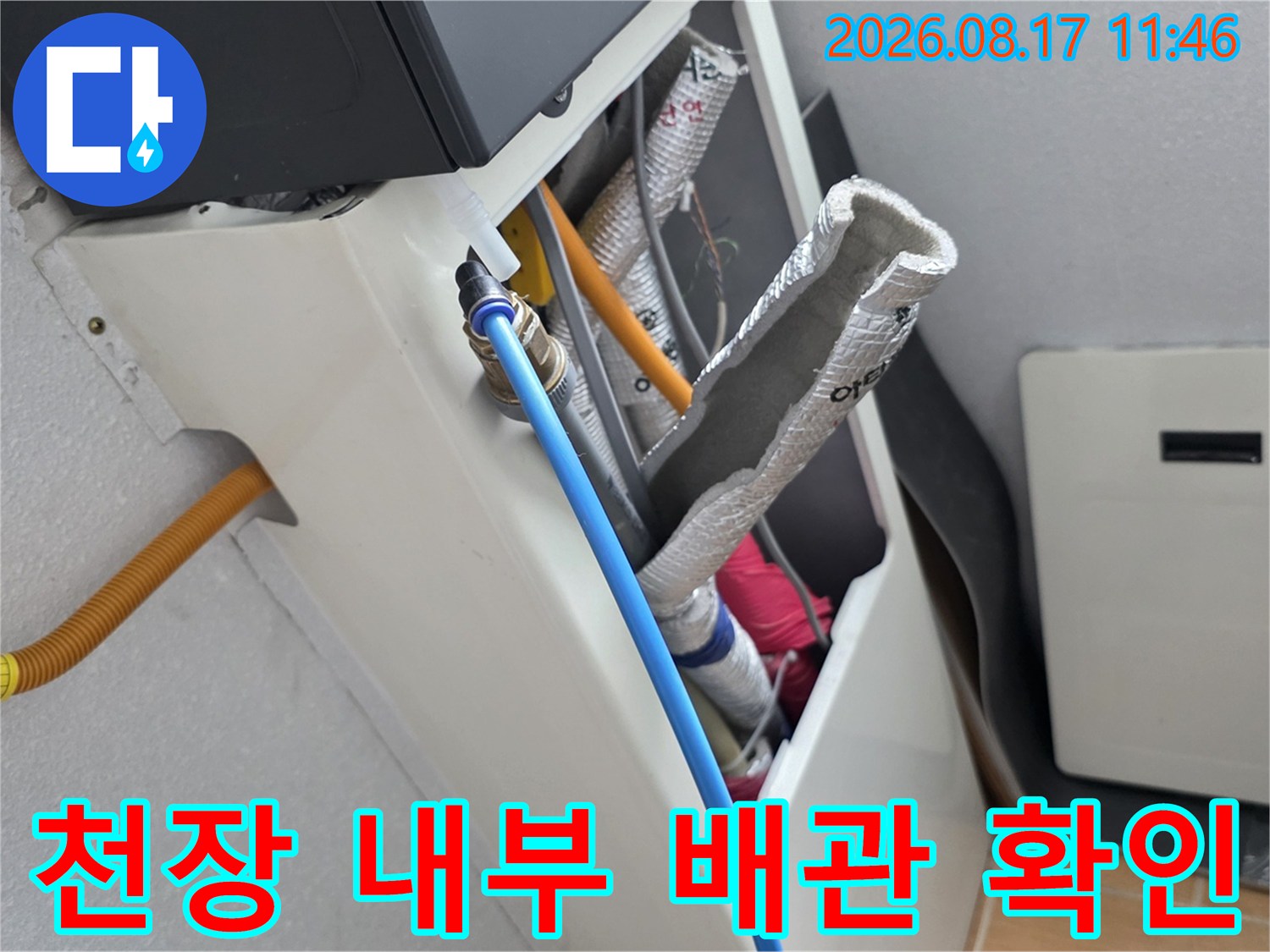 보온재로 감싸진 배관과 파란색 호스가 연결된 천장 내부 구조