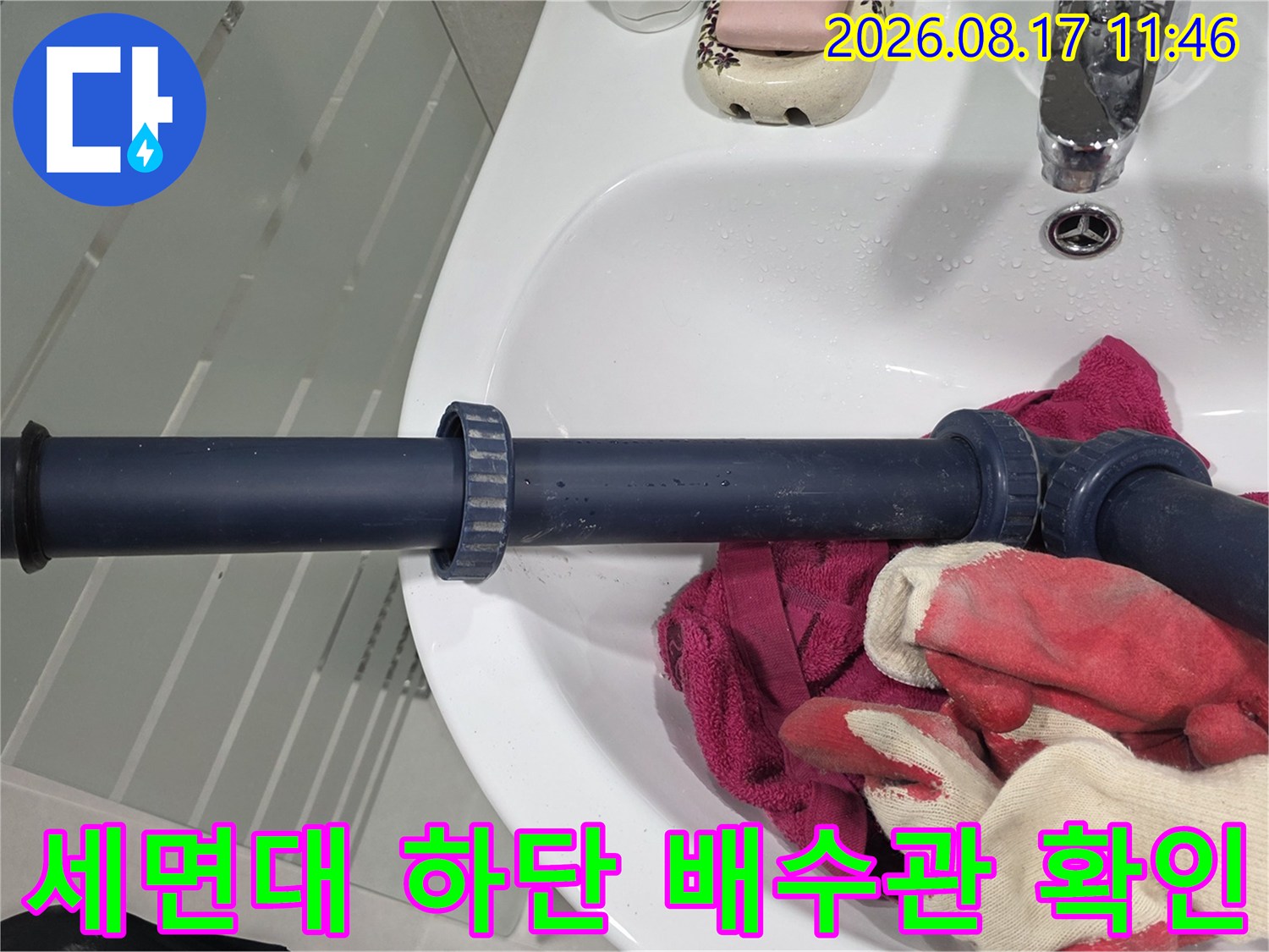 세면대 아래쪽의 어두운색 배수 배관을 클로즈업한 사진입니다