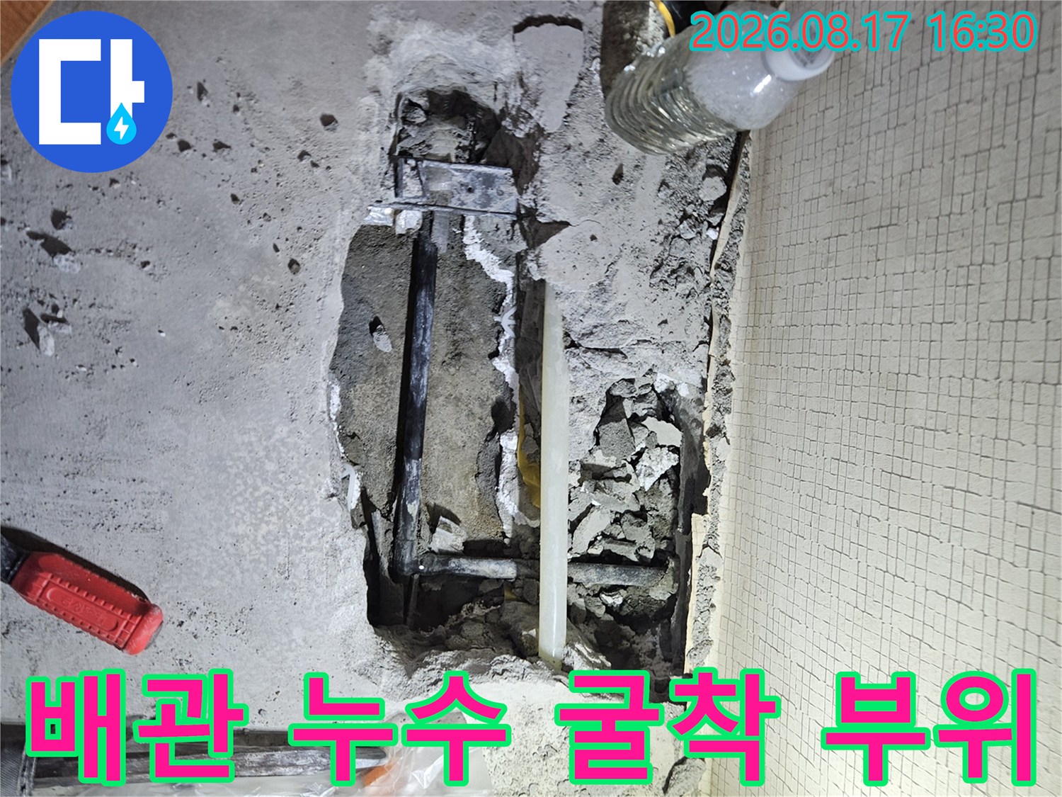 콘크리트 바닥을 파내어 드러난 배관과 주변 작업 도구들
