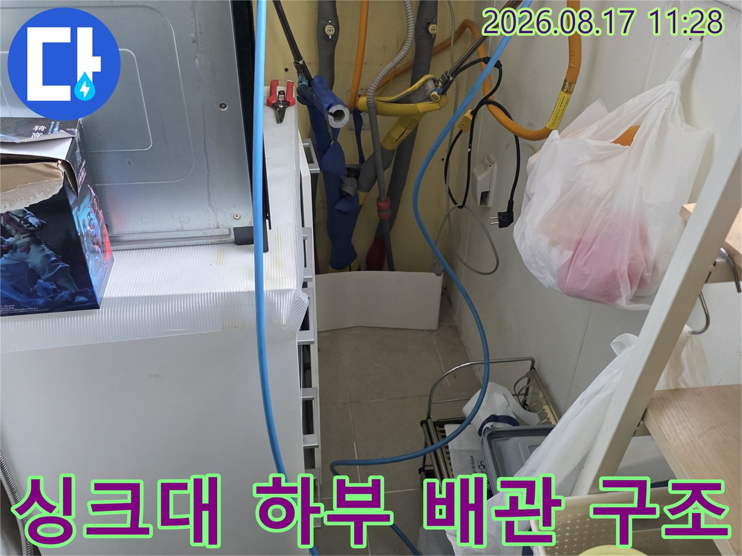 주방 싱크대 하단에 설치된 수도 배관과 정수기 라인의 복잡한 배치 상태