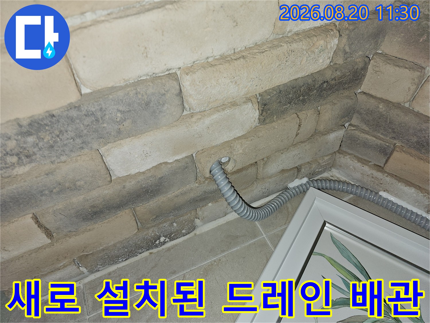 석재 벽면 틈 사이로 노출된 새로운 에어컨 배수 호스