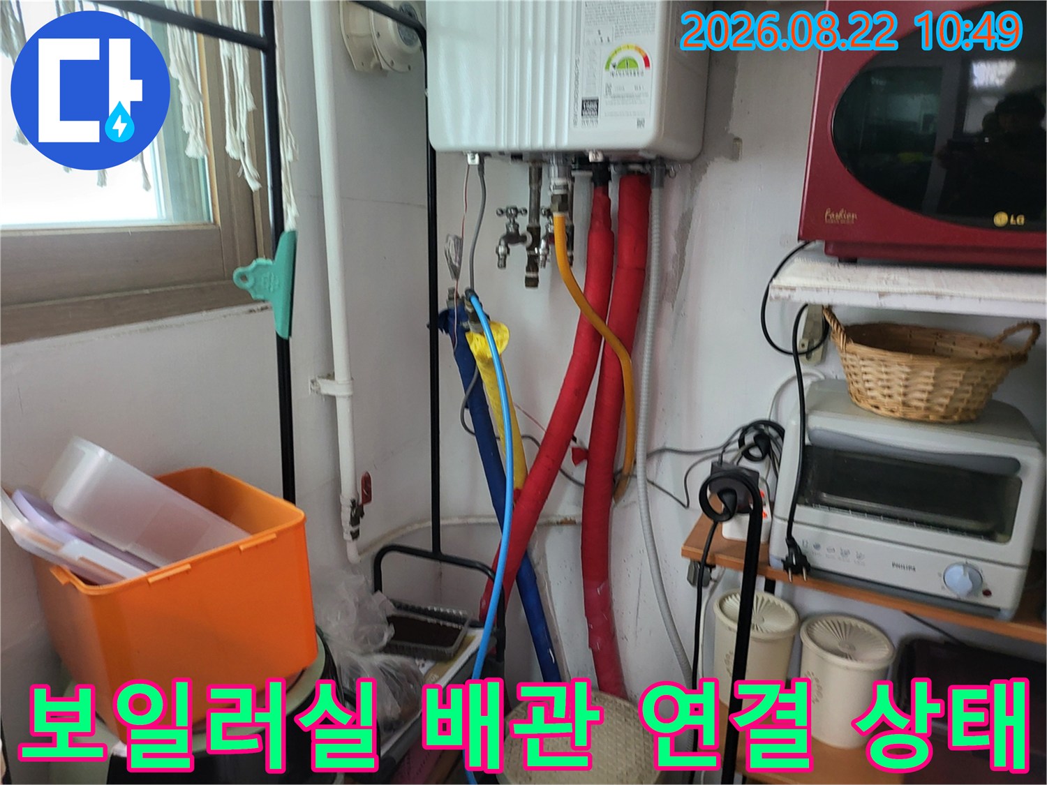 보일러 하단에 설치된 붉은색과 파란색 주름관의 결합 부위를 촬영한 사진입니다.