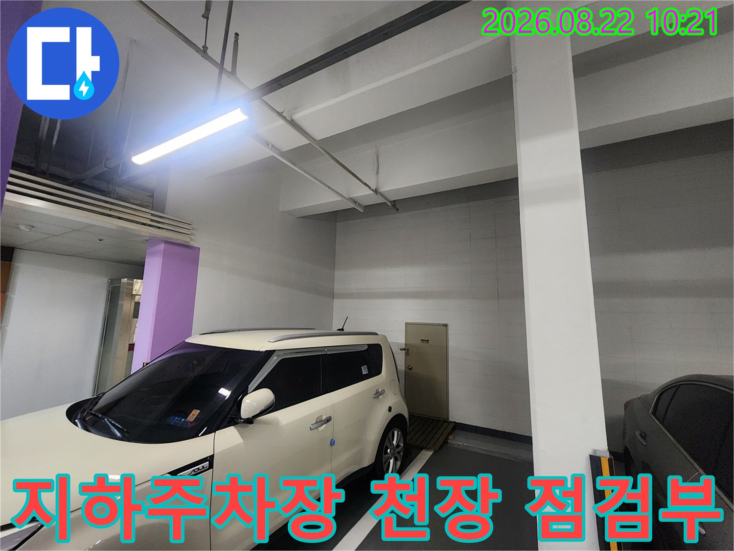밝은 조명이 비치는-지하주차장 내부의 배관 및 천장 구조입니다.
