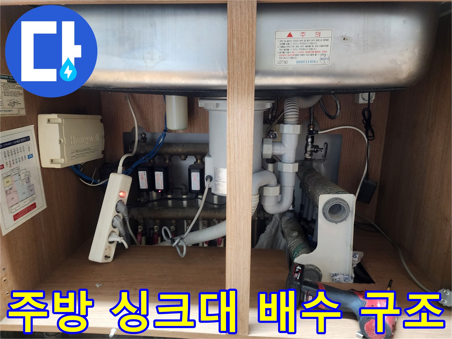 싱크대 아래쪽의 복잡하게 연결된 배수 호스 및 부속품