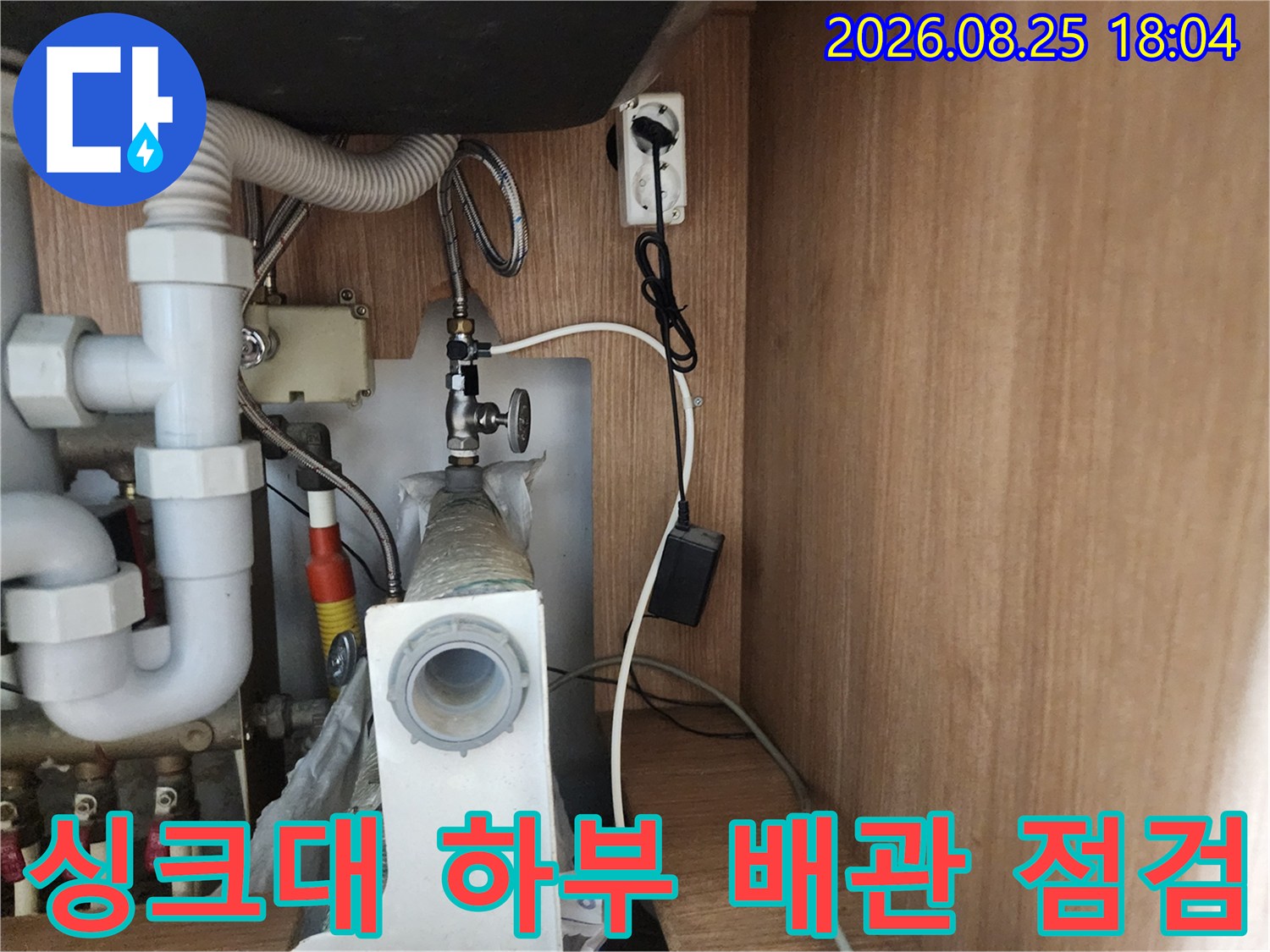 싱크대 아래쪽의 복잡한 배관과 급수 밸브를 촬영한 사진입니다.
