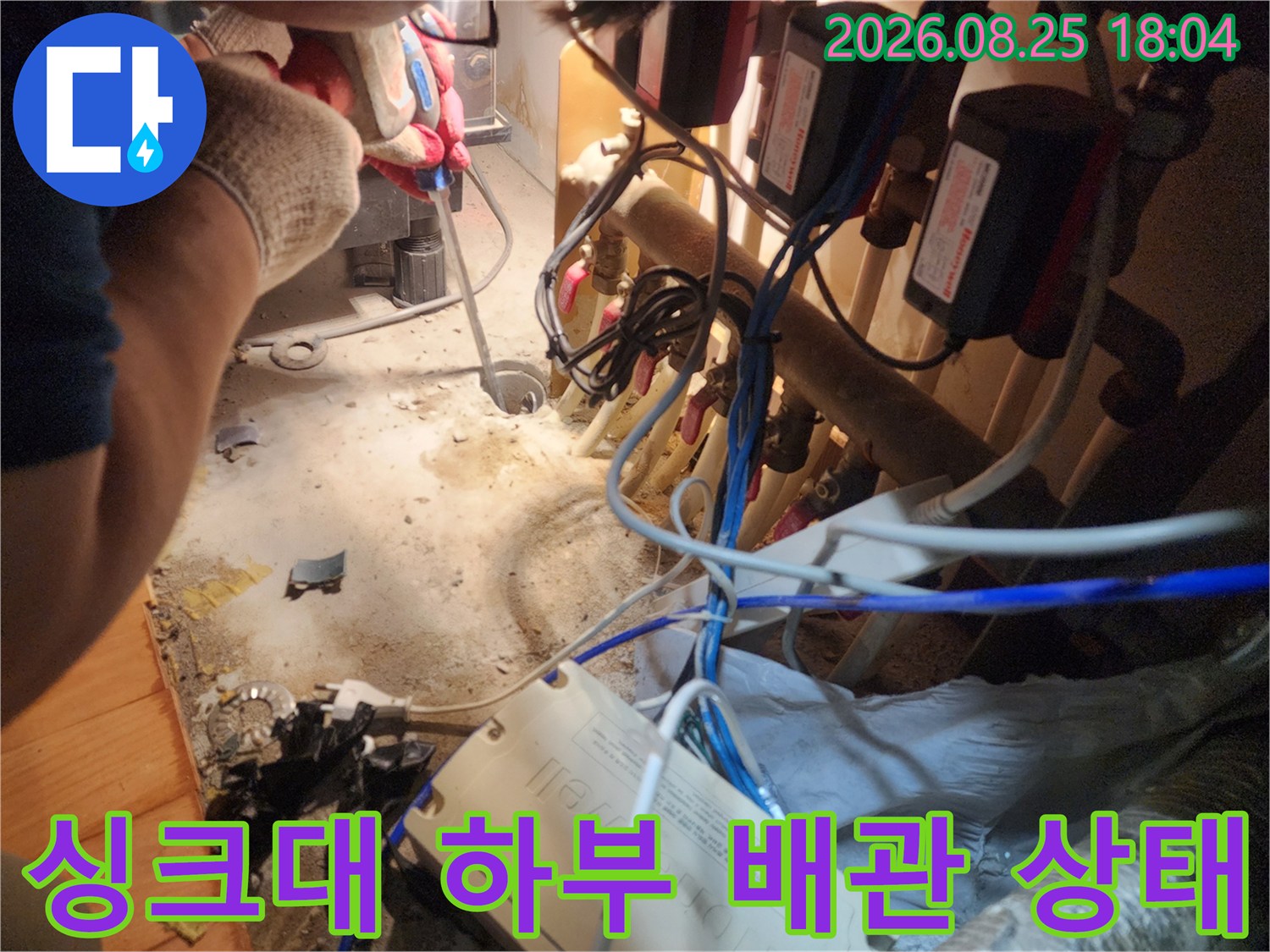 싱크대 아래쪽의 복잡한 밸브 장치와 연결된 배수관 모습
