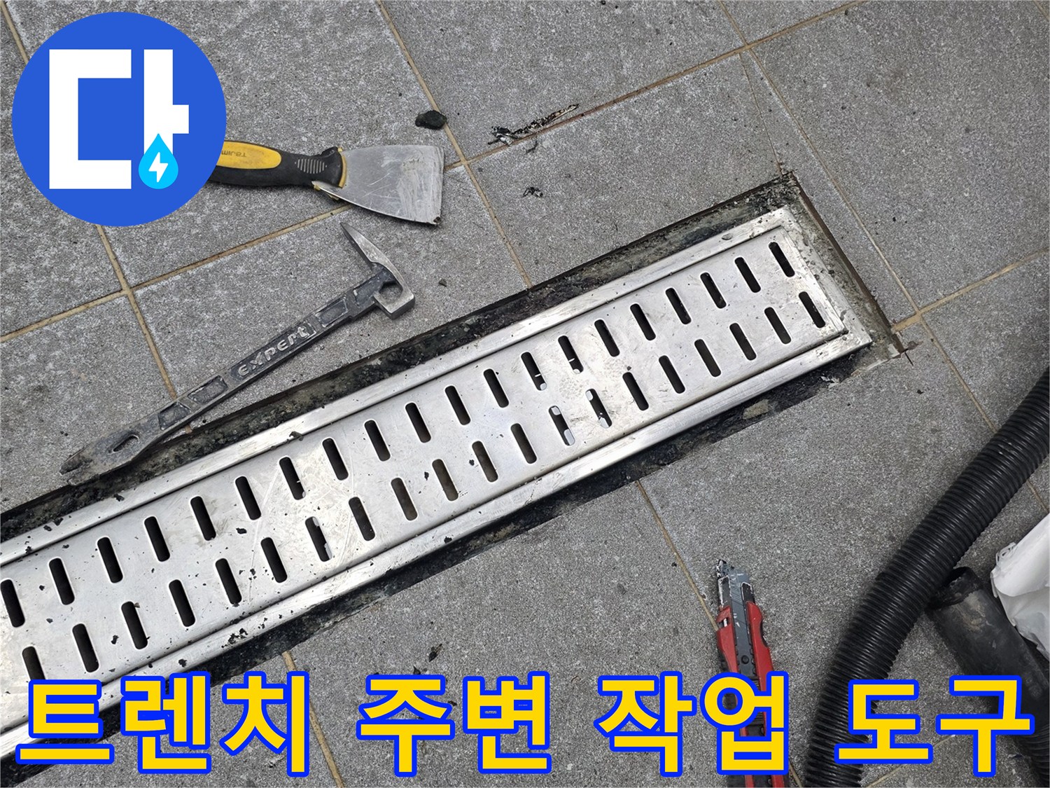 배수 트렌치 덮개가 제거된 바닥과 수리용 헤라 및 칼