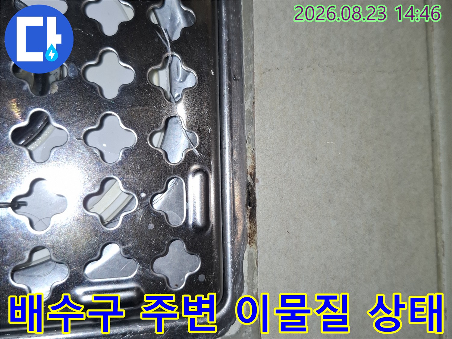 스테인리스 배수구 덮개와 타일 사이의 오염된 모습을 보여줍니다.