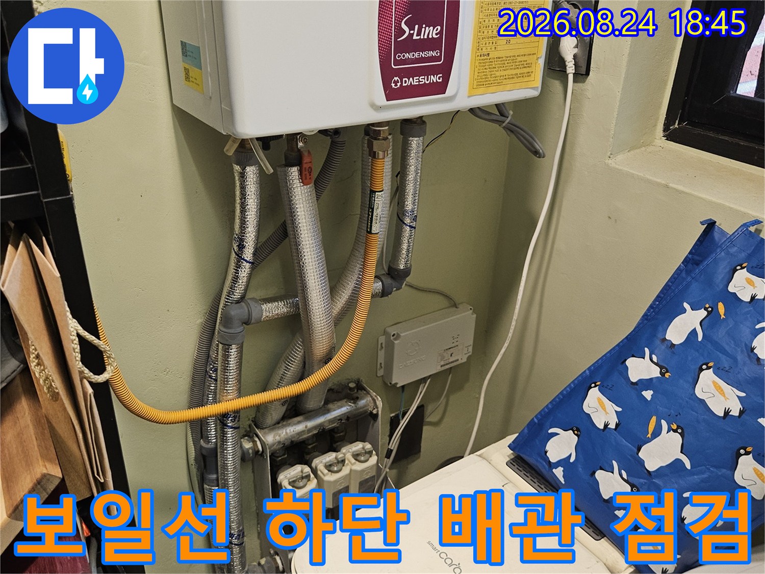 은색 보온재로 마감된 보일러 배관과 노란색 급수 호스 상세 컷
