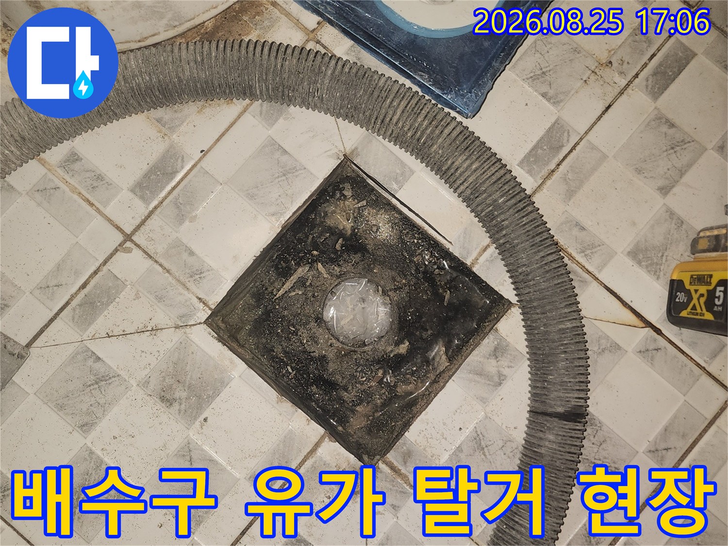 탈거된 배수구 주변의 오염된 타일과 노출된 배관 부속입니다.