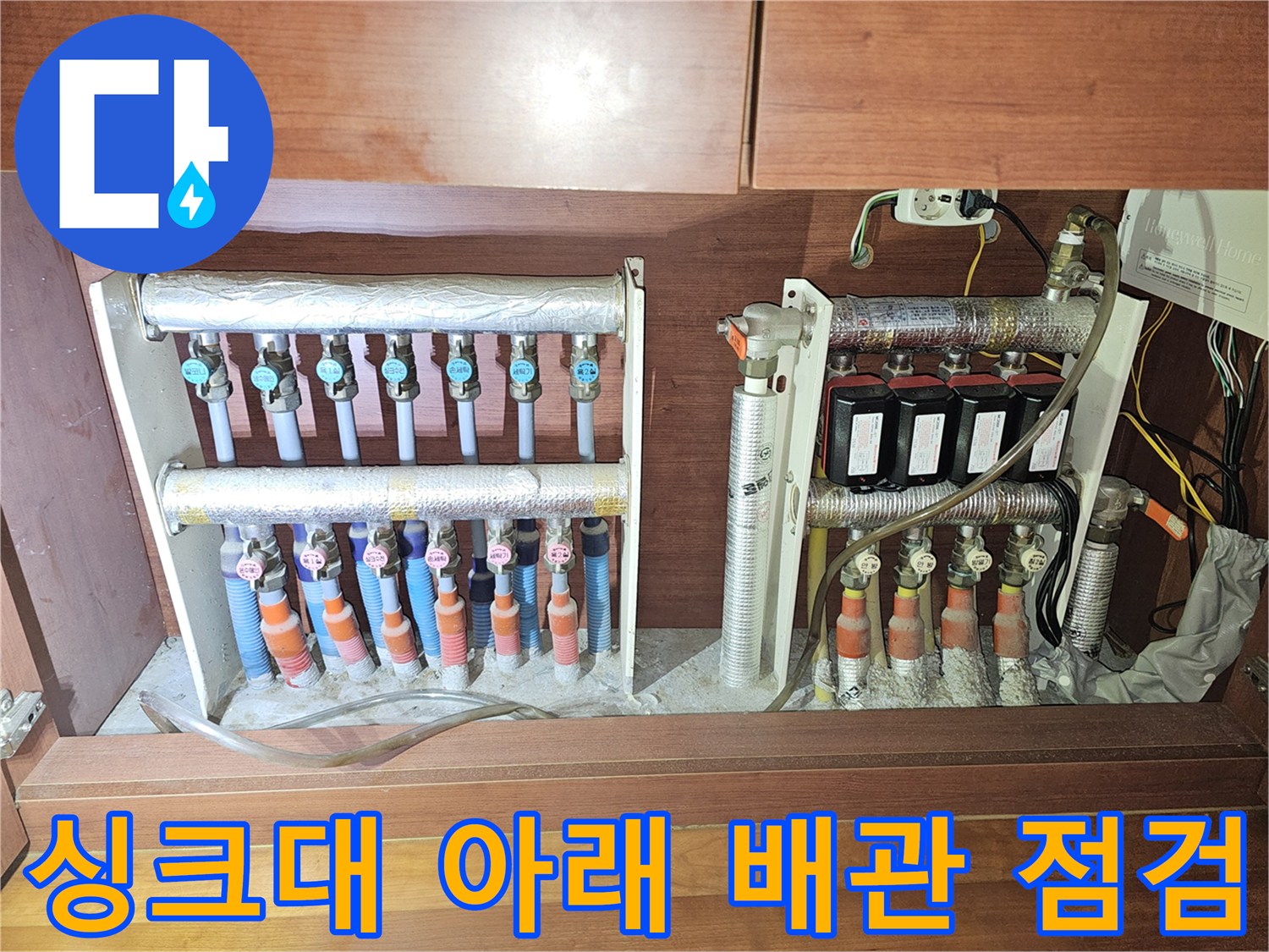 싱크대 하부장 내부의 복잡한 배관 및 분배기 배열