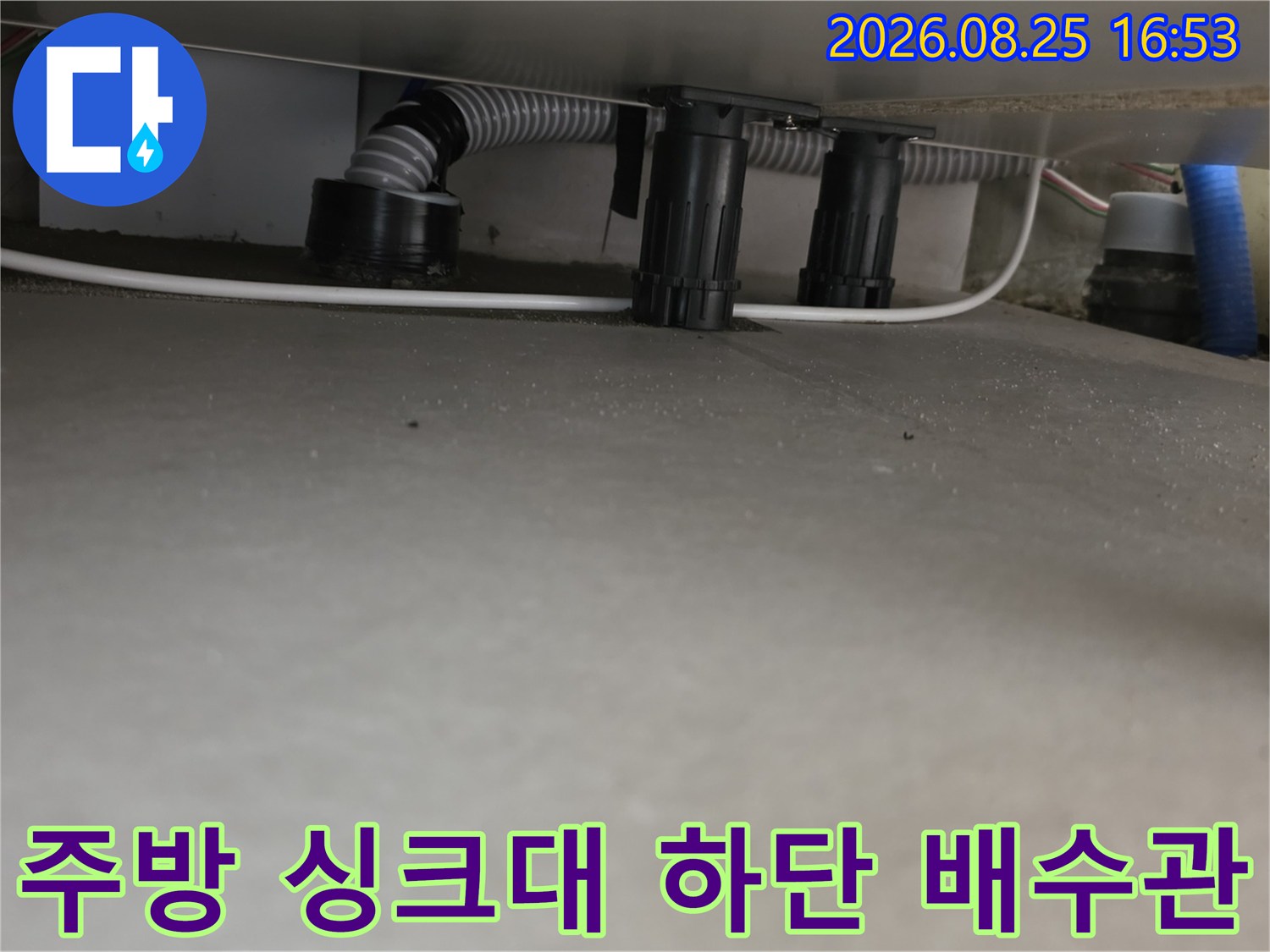 싱크대 아래쪽의 주름진 호스와 검은색 연결 부속품 사진입니다.