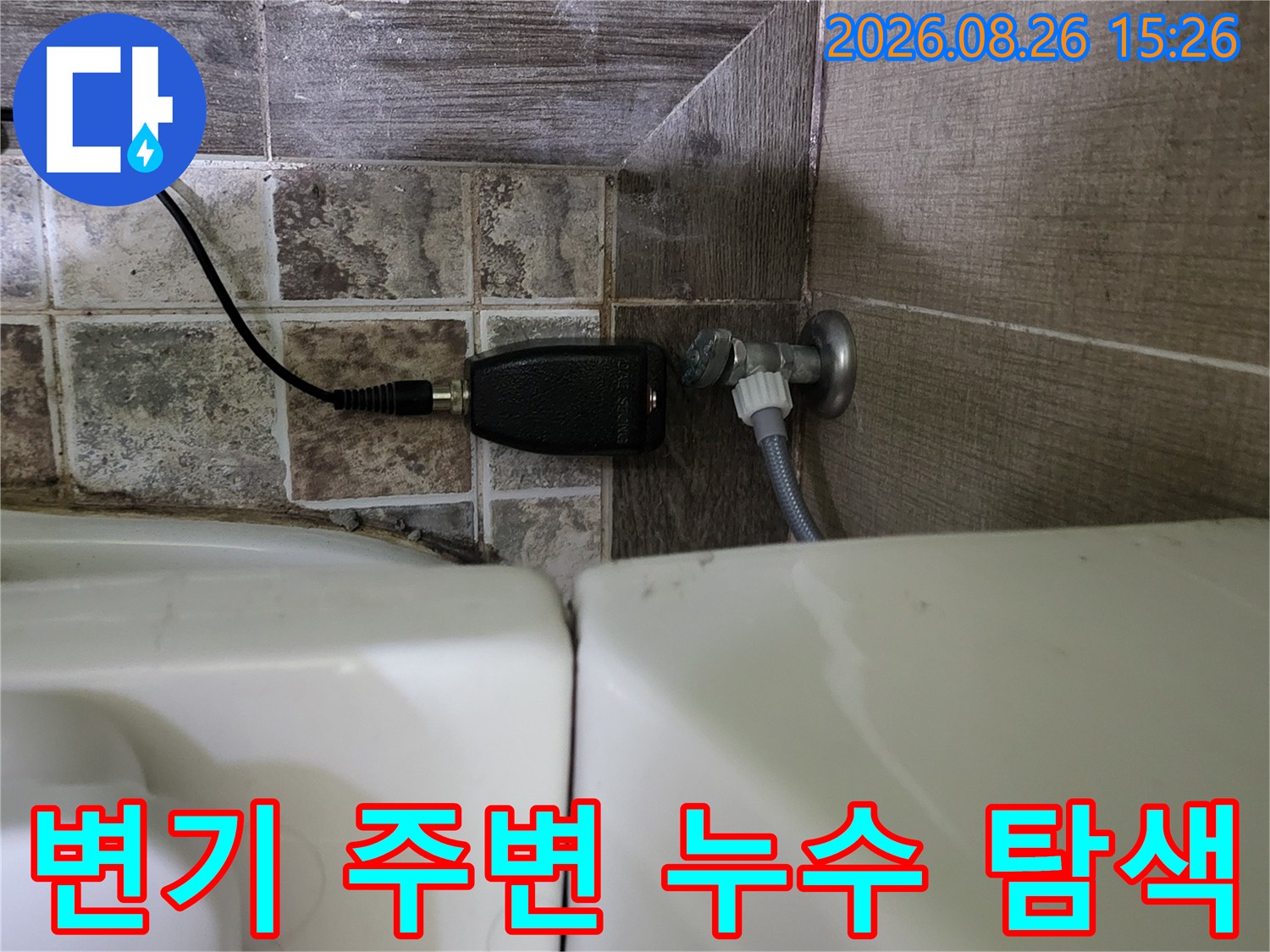 변기 뒤쪽 배관 부근에 가스식 탐지 장비를 연결해 놓은 장면입니다.