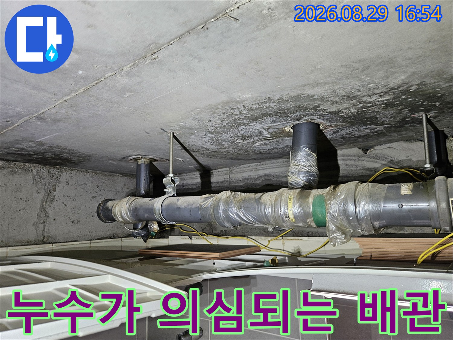 검은 얼룩이 퍼져 있는 천장 내부의 배관 구조물