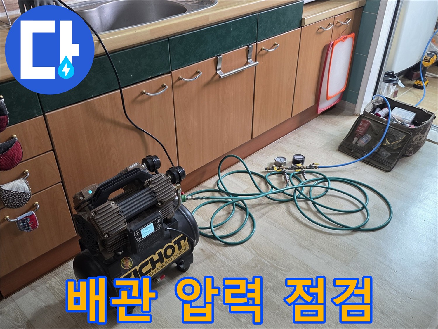 싱크대 아래 배관에 연결된 공압 측정 장비와 호스
