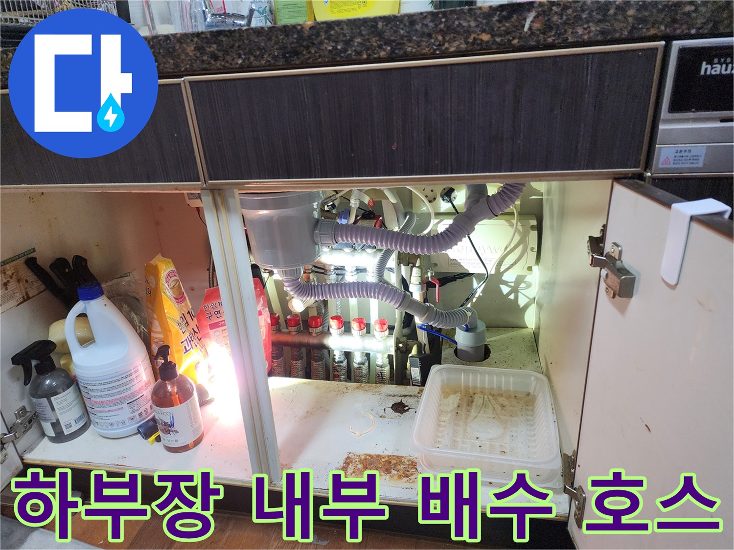 싱크대 아래쪽-연결된 은색 자바라 배관과 에어컨 배수 라인