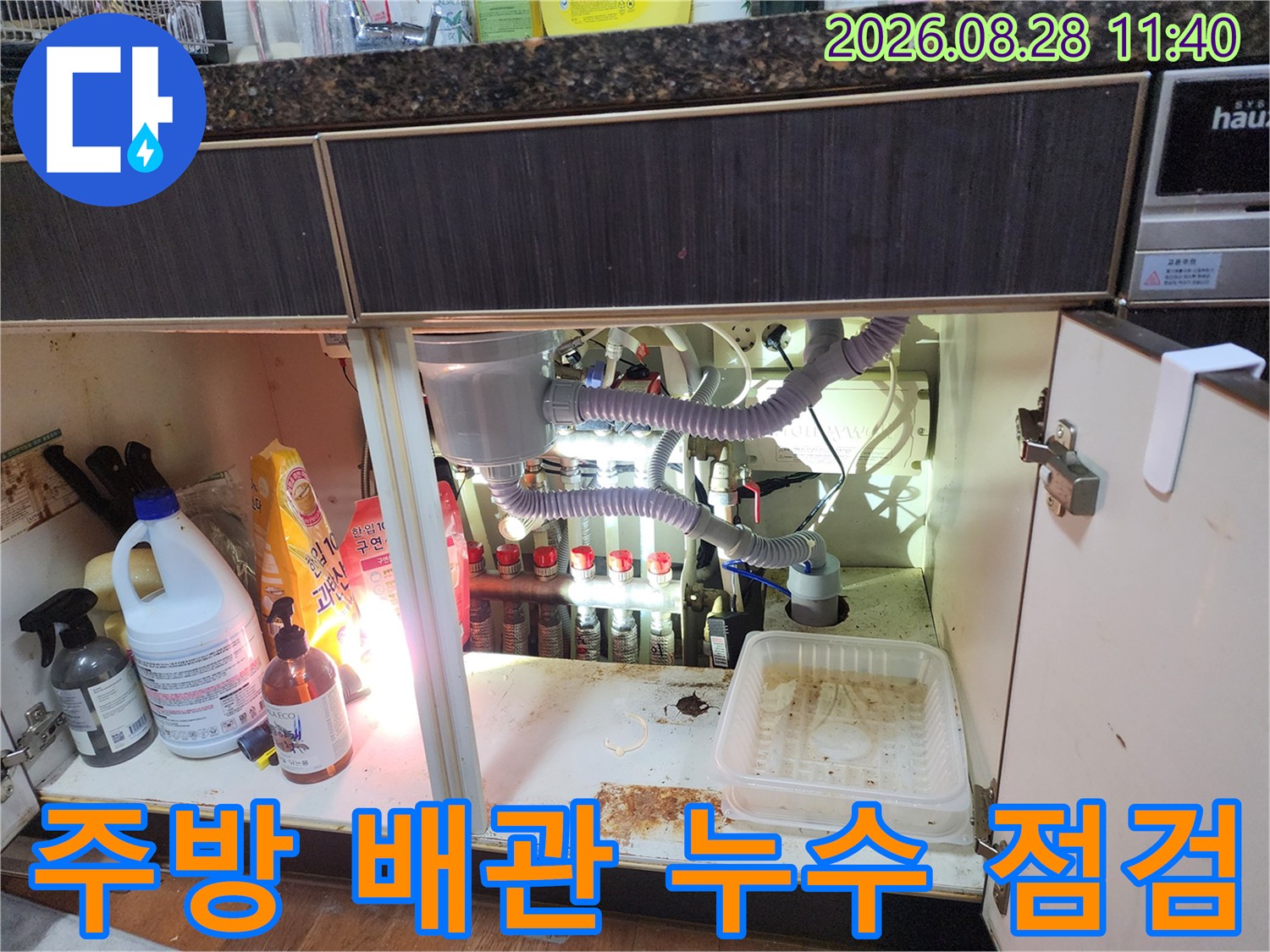 싱크대 하부 배관의 연결 상태와 주변 오염도를 확인하는 작업 과정