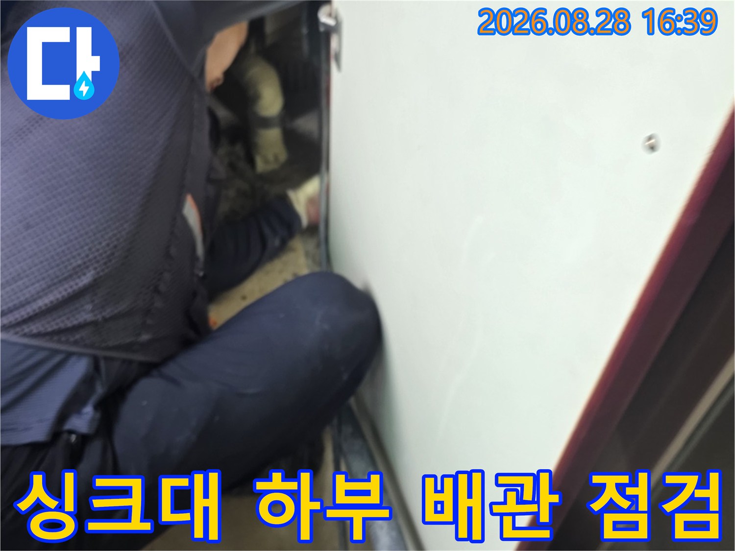 싱크대 하부장 아래쪽에서 작업자가 배관 상태를 면밀히 확인하고 있습니다.