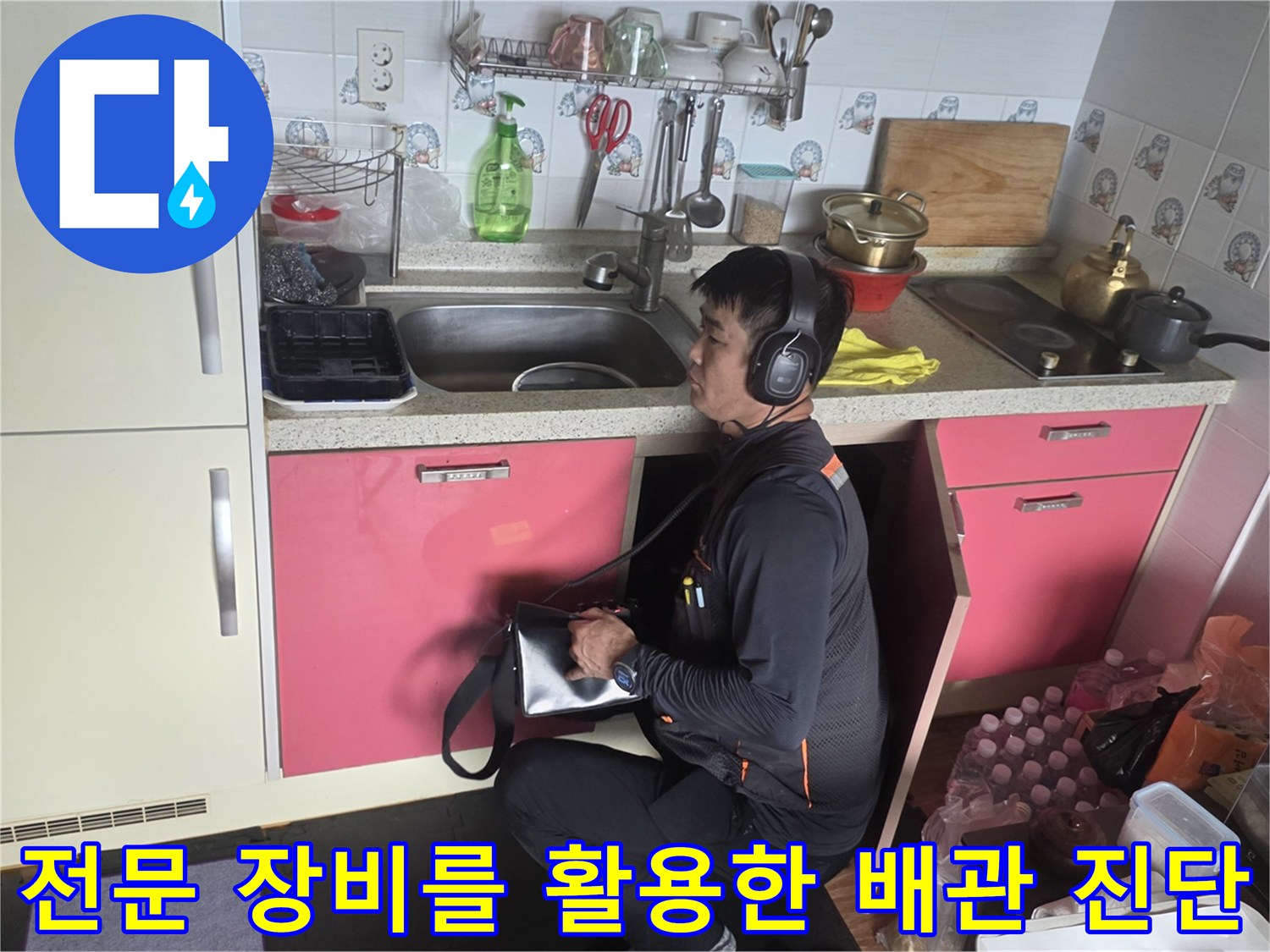 청음 탐지 헤드셋을 착용한 엔지니어가 싱크대 하부 배관 소리를 듣는 장면