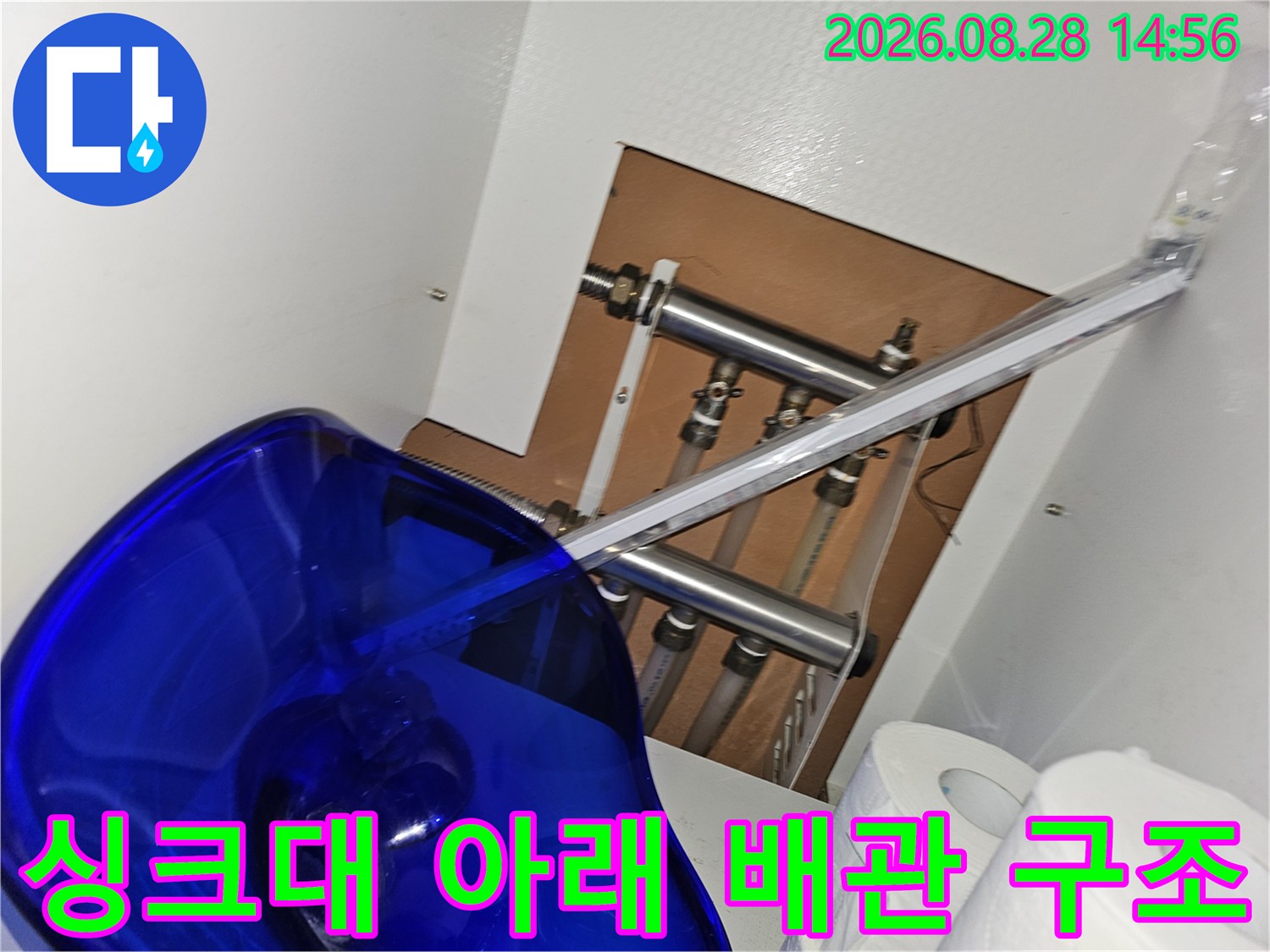 싱크대 밑 공간에 노출된 보일러 및 수도 연결 배관들의 모습입니다.