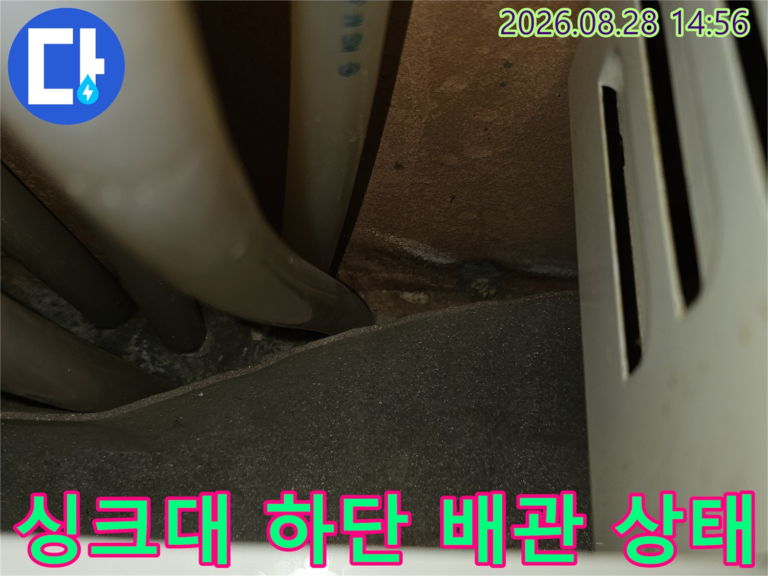 싱크대 아래쪽 좁은 공간의 배관 연결 부위를 촬영한 사진입니다.
