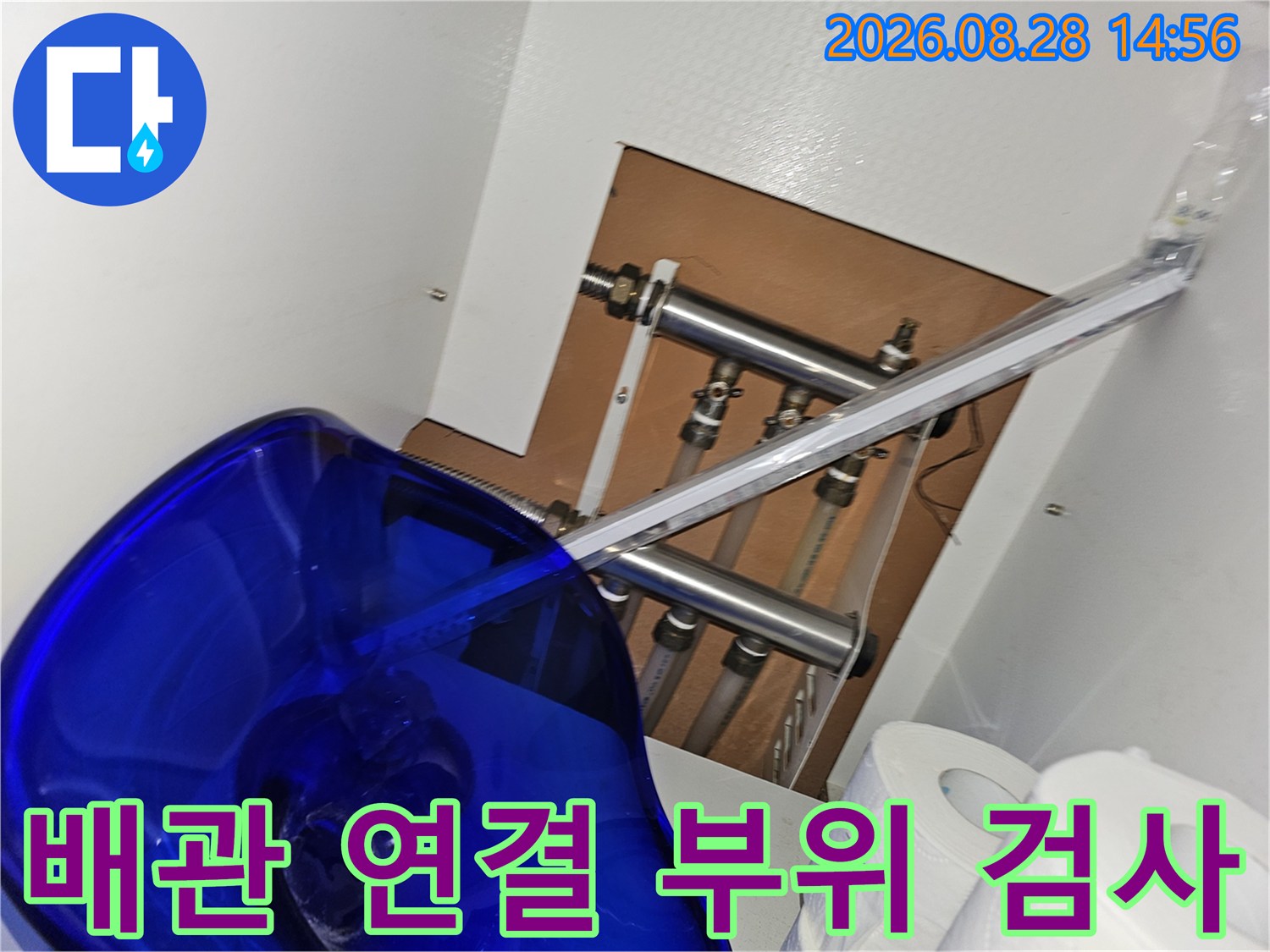 싱크대 하부의 금속 배관들과 연결된 밸브 및 조인트들의 모습입니다.