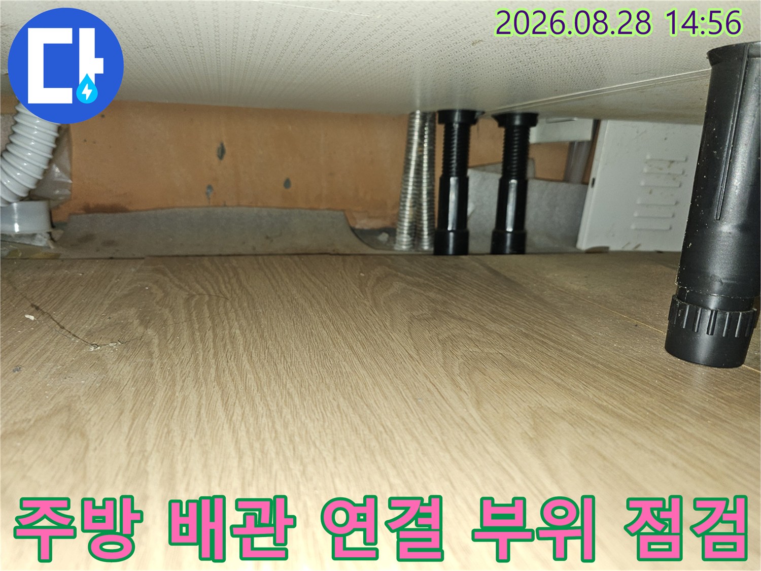 싱크대 하부장 내부의 수직 배관 및 주름 호스 상세 모습