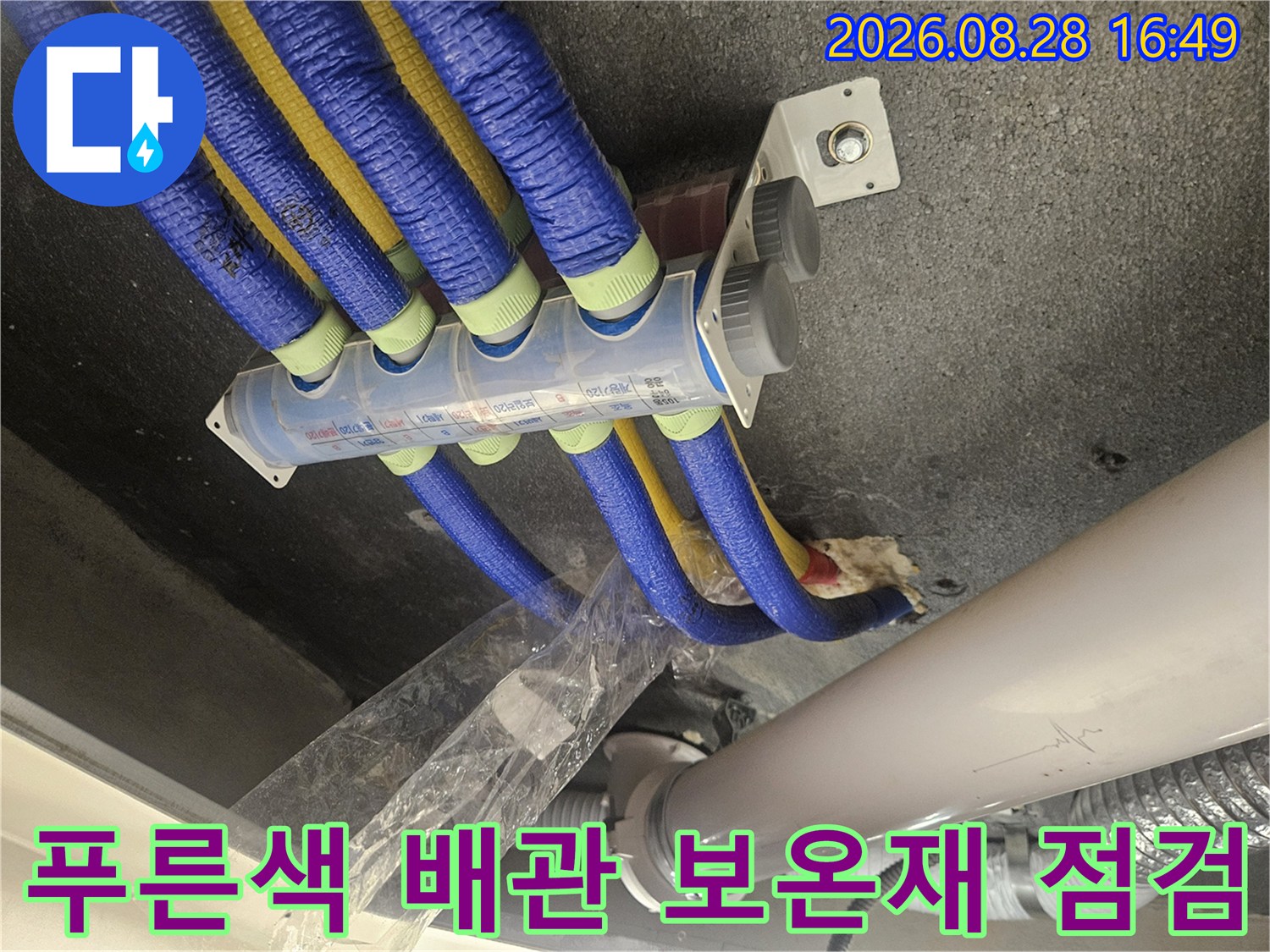 푸른색과 노란색 보온재로 감싸진 화장실 천장 내부 배관 모습입니다.
