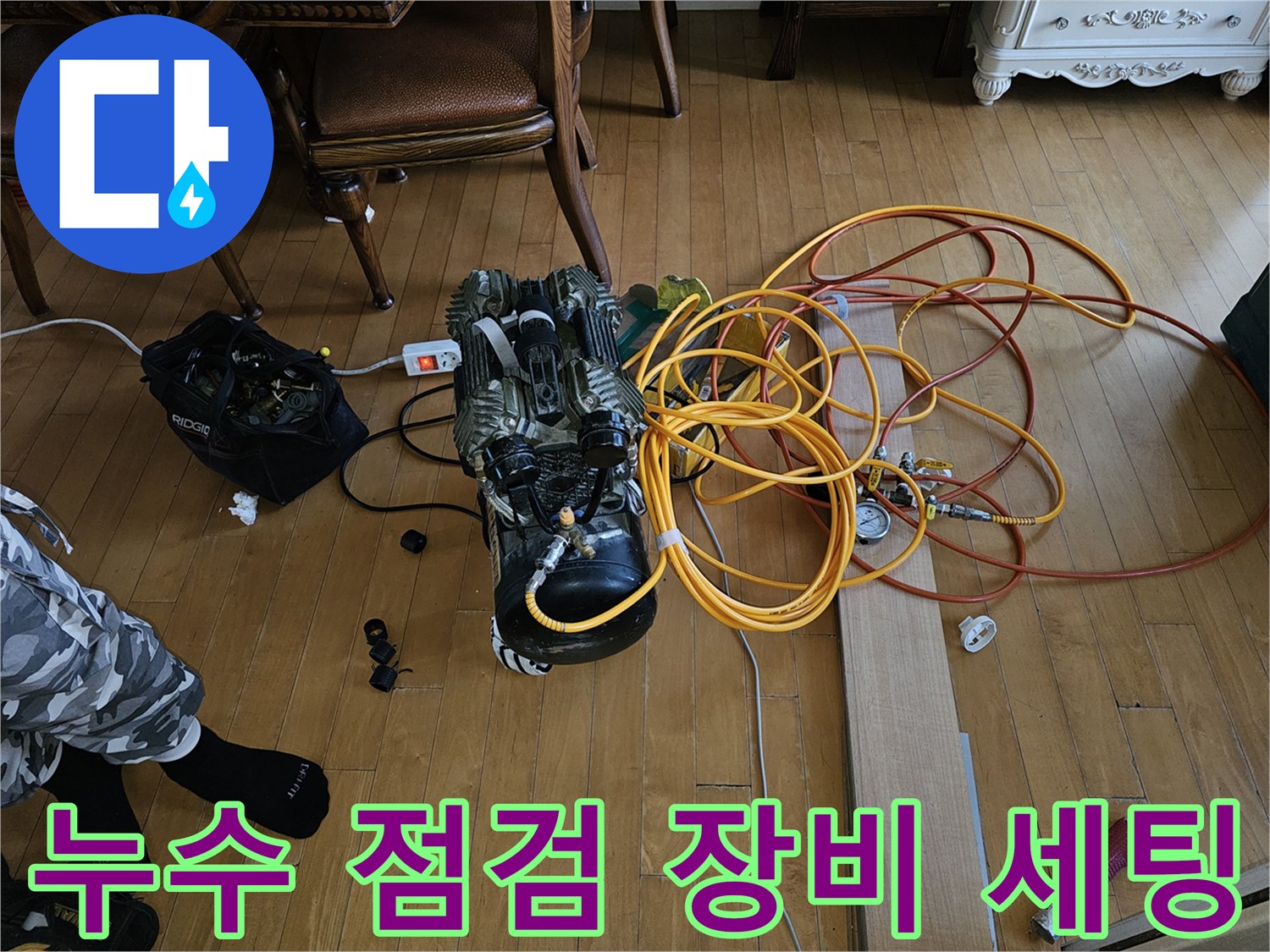바닥에 놓인 공기 압축기와 노란색 및 빨간색 에어 호스 연결 상태