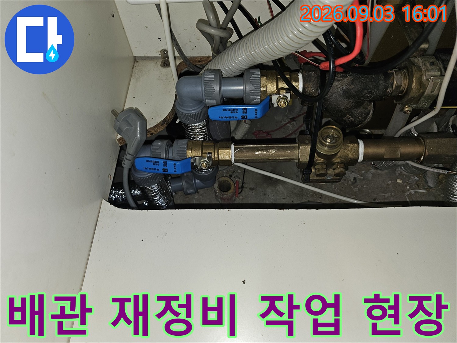 복잡하게 얽힌 싱크대 하부 배관과 파란색 조절 밸브의 모습