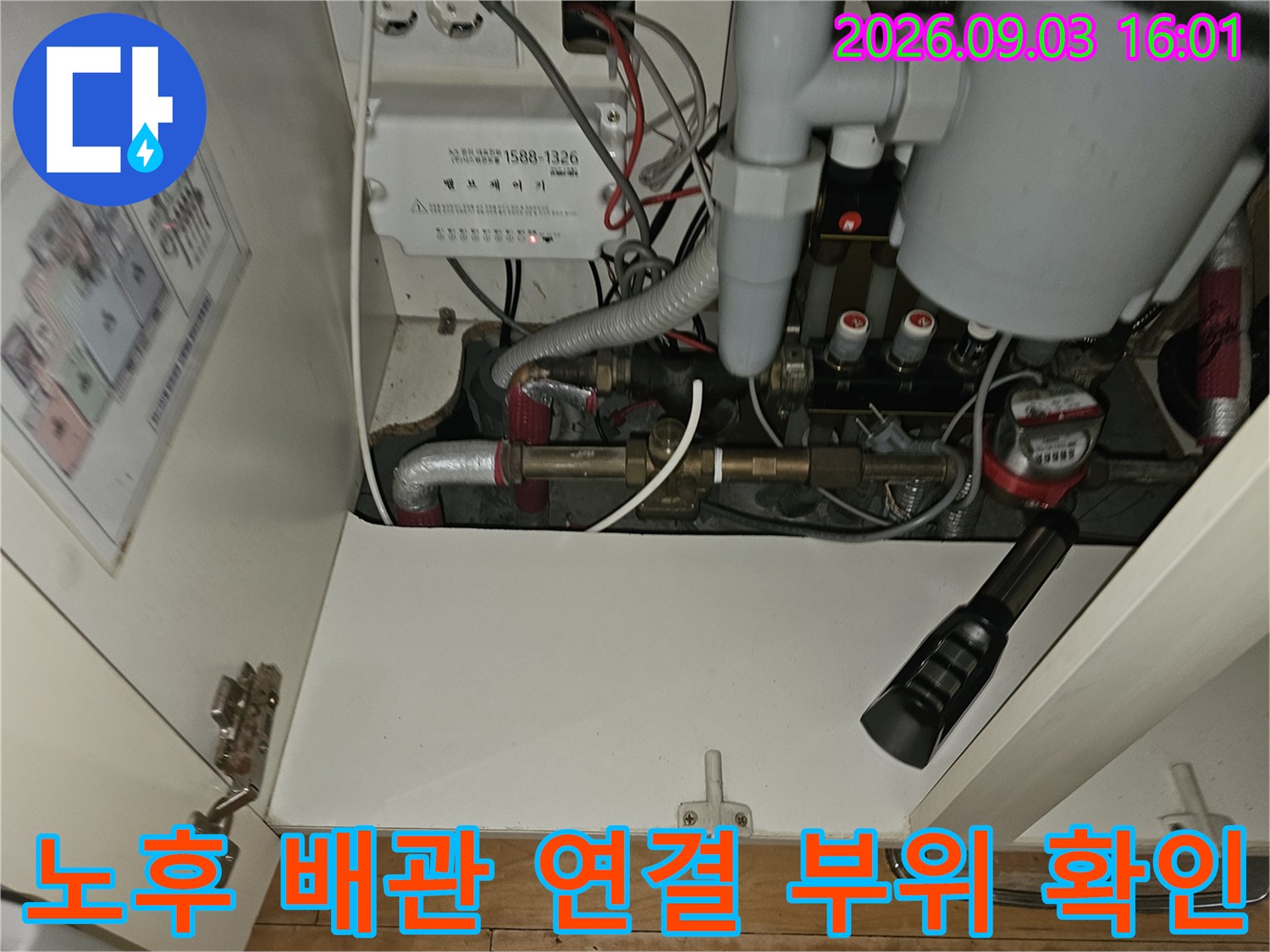 싱크대 하부장 안쪽의 난방 배관과 각종 연결 부품 상세 사진
