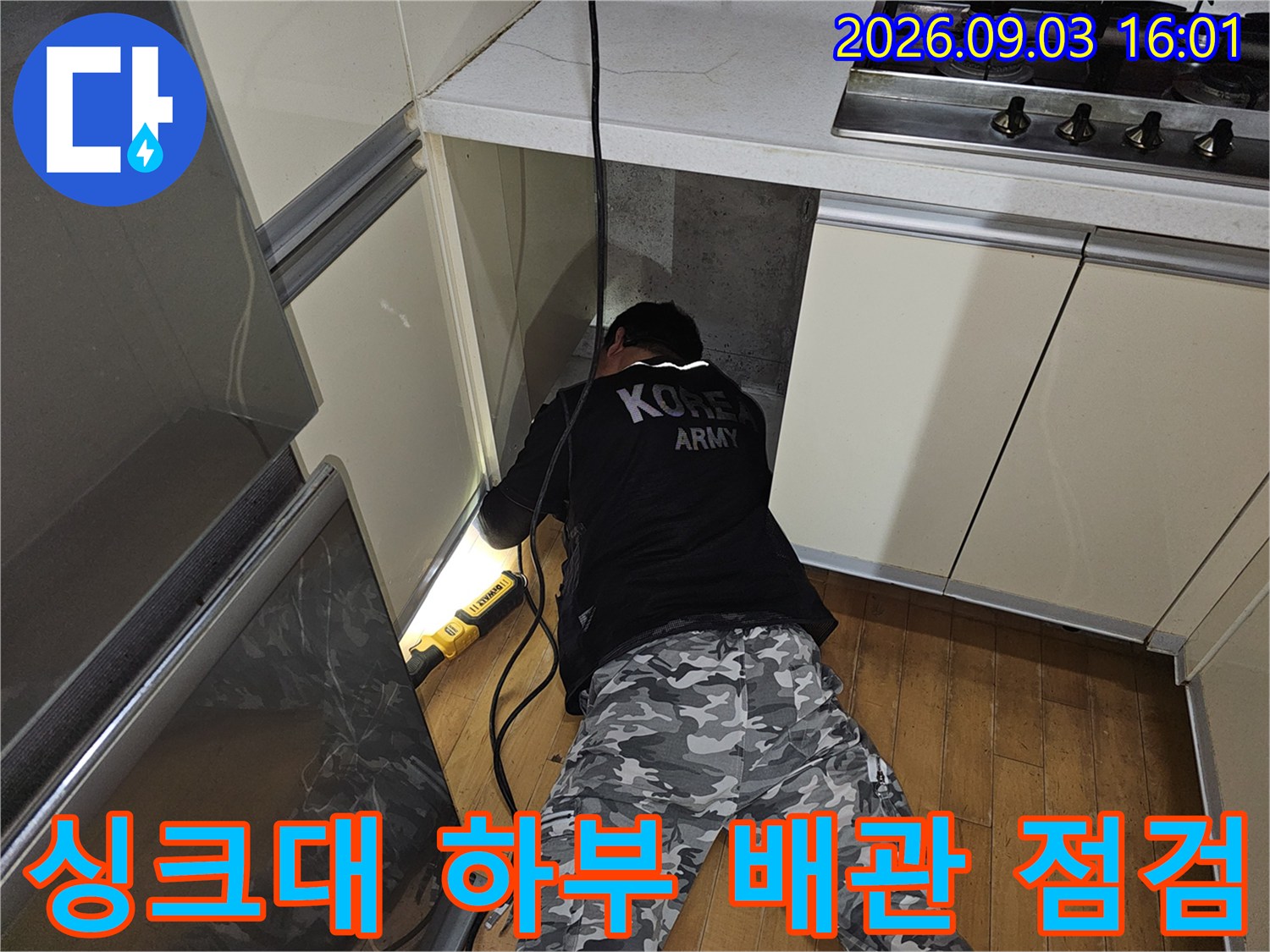 좁은 싱크대 하단 공간에서 작업 중인 배관 공사 현장 사진