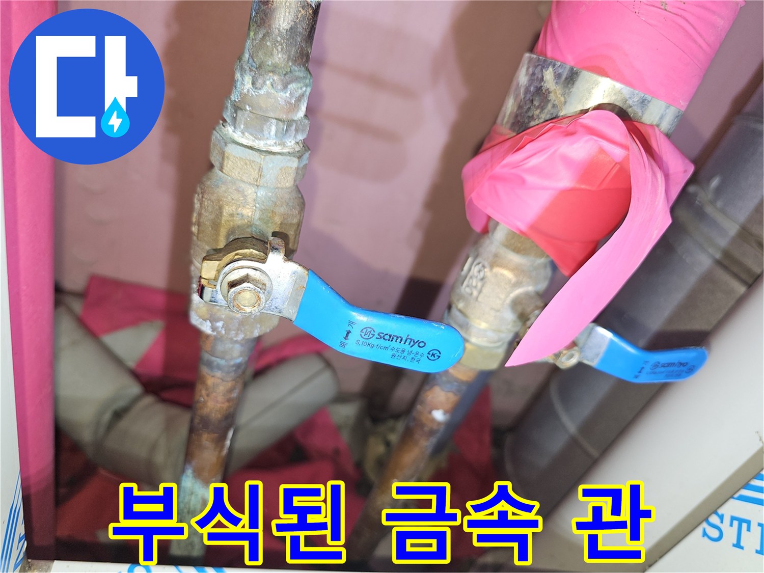 파란색 밸브 핸들이 달린 부식된 금속 배관의 모습