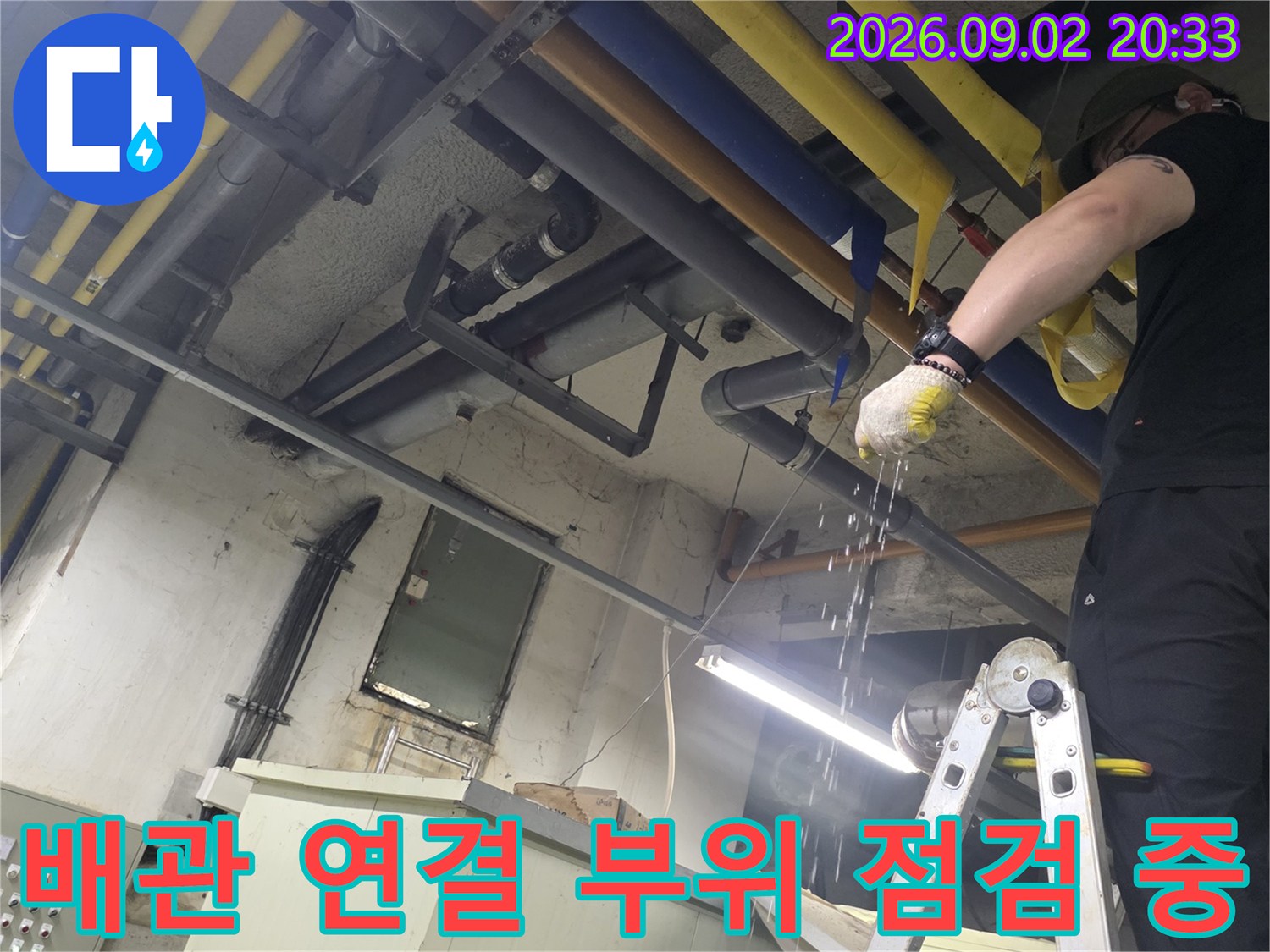 작업자가 사다리 위에서-천장 배관의 누수 지점을 찾는 모습