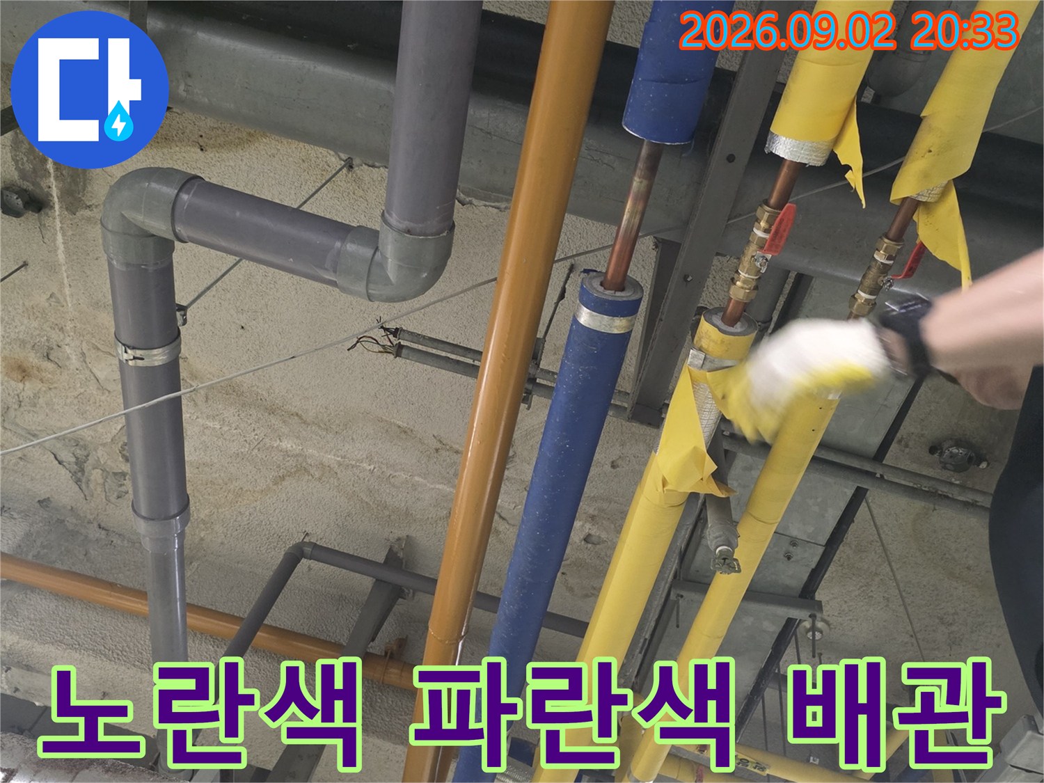 천장 배관 구조-보온재로 감싸진 노란색과 파란색의 배관 설비들