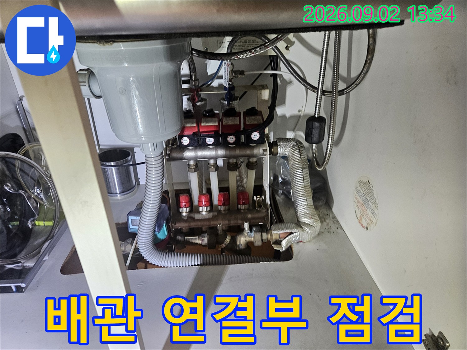 보일러 분배기 밸브와 유연한 호스 연결 부위를 근접 촬영한 사진입니다.