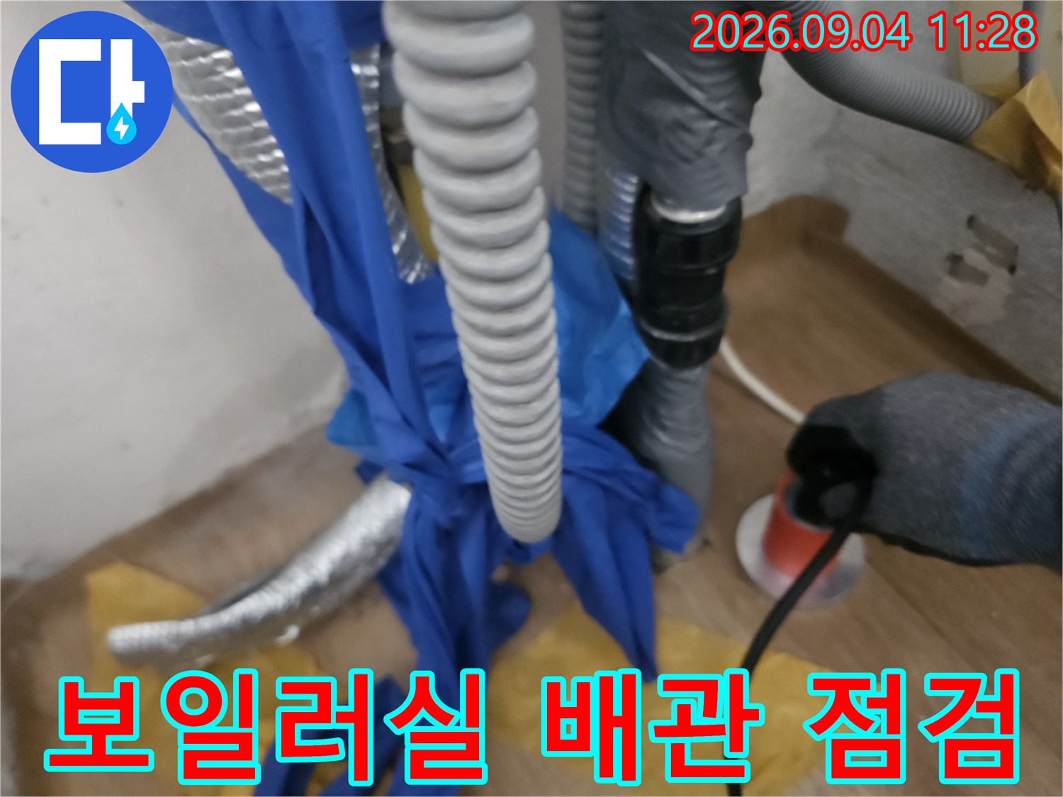 파란색 비닐로 감싸진 보일러실의 배관 작업 현장