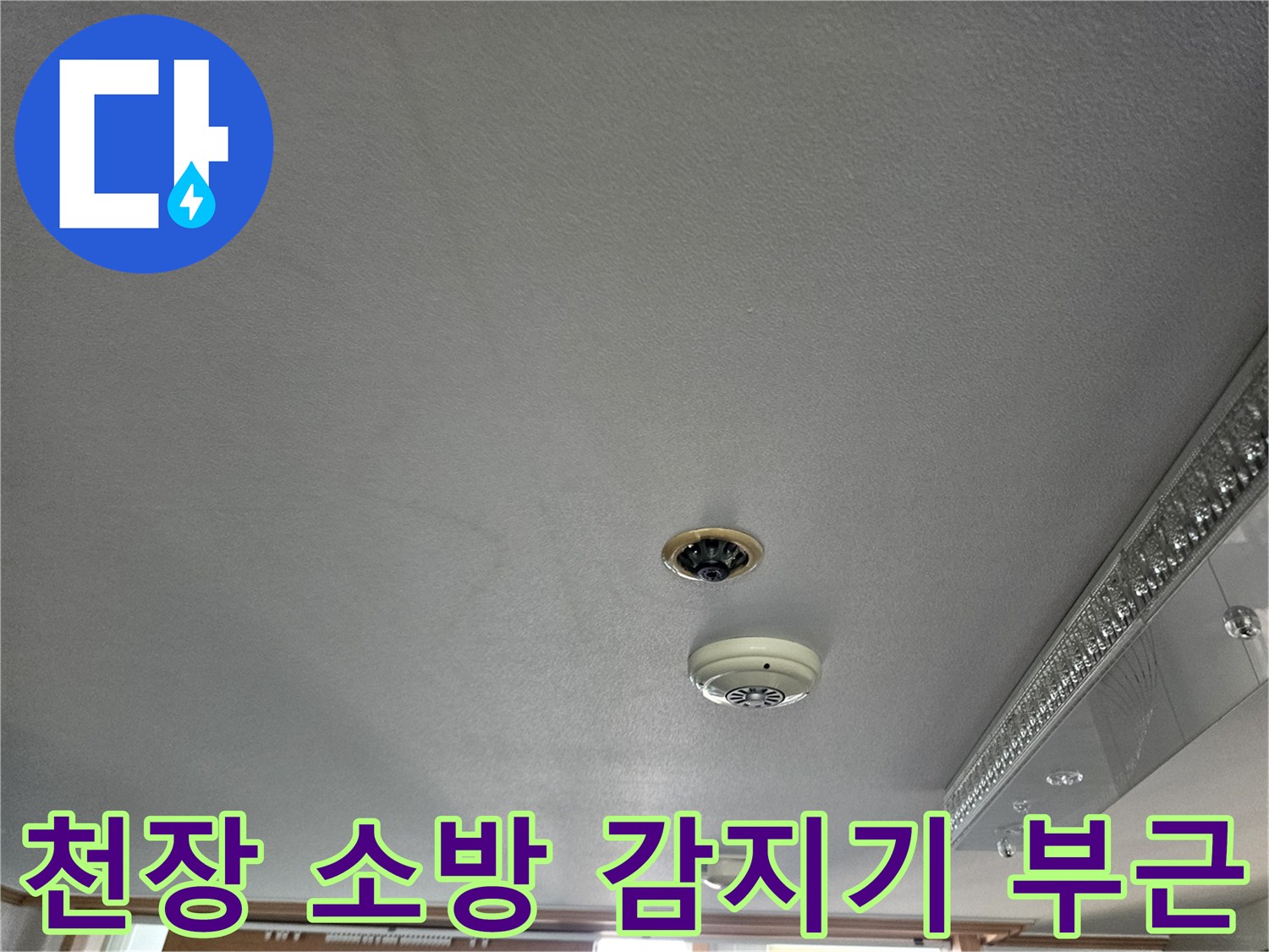 거실 천장에 위치한 화재 감지기와 매립 배관 점검 부위