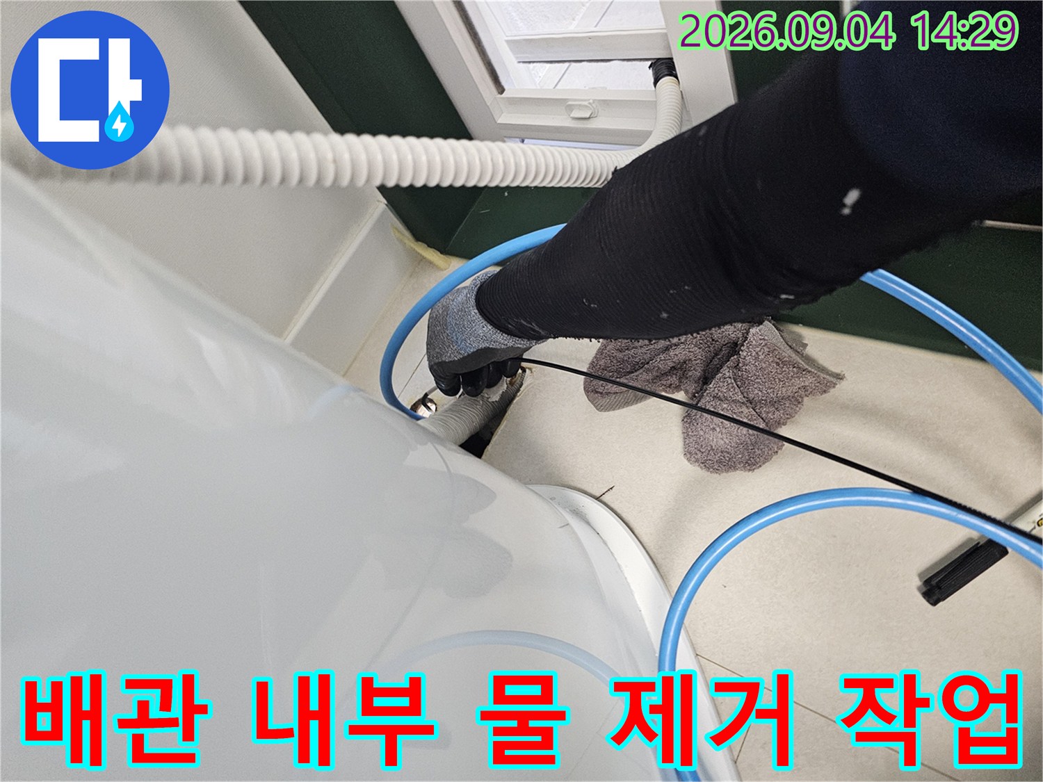 검은색 장갑을 착용한 엔지니어가 배관 내부를 점검하며 잔수를 흡입하고 있습니다.