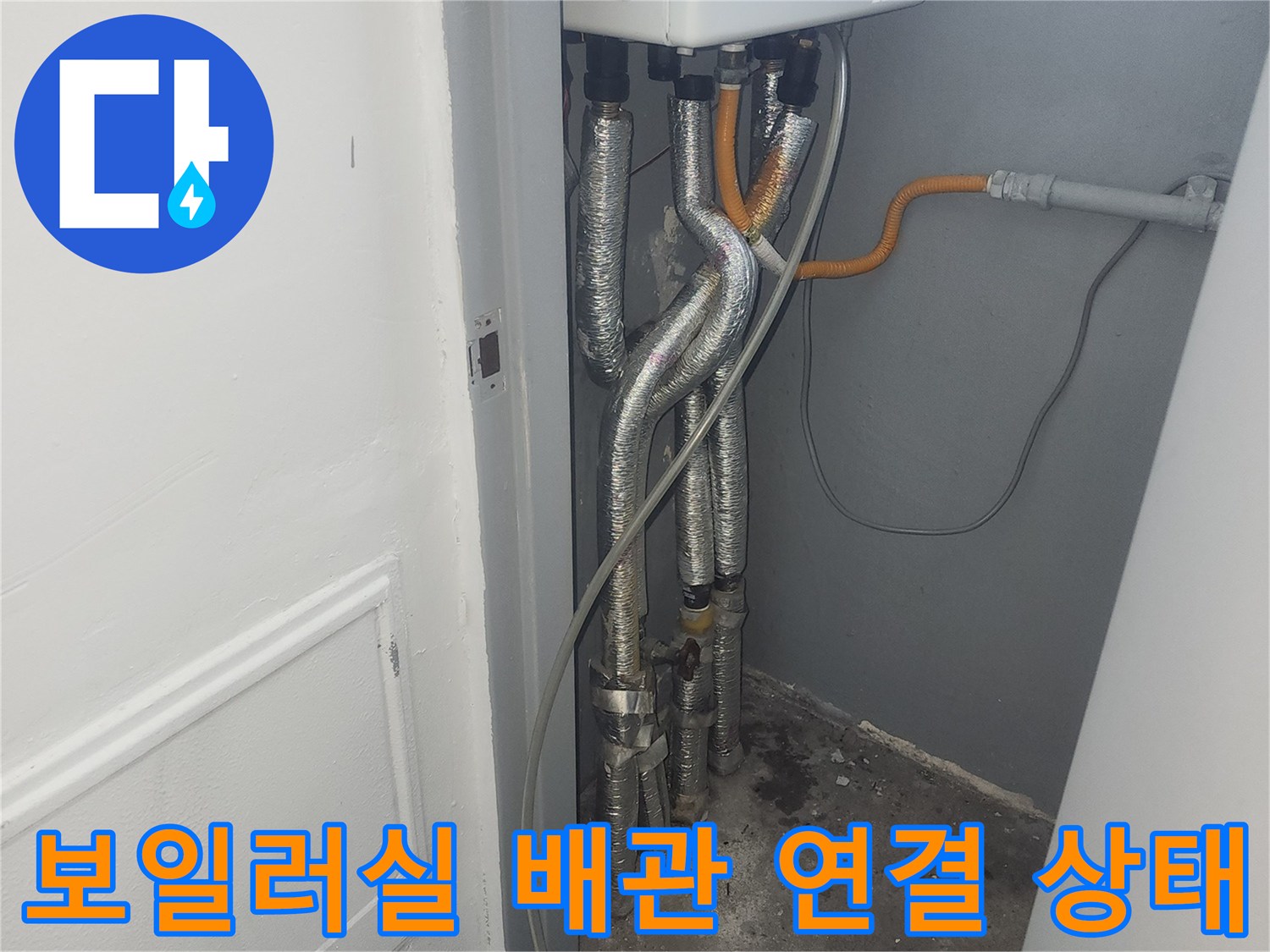 보일러 하단에 연결된 은색 주름관과 노란색 가스배관의 모습입니다.