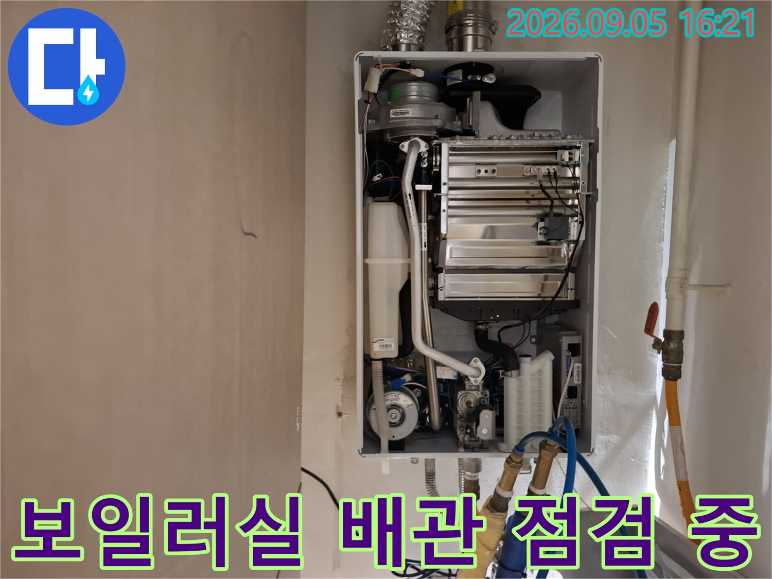 보일러 하단부의 복잡한 밸브와 배관 연결 상태를 세밀하게 관찰하는 사진입니다.