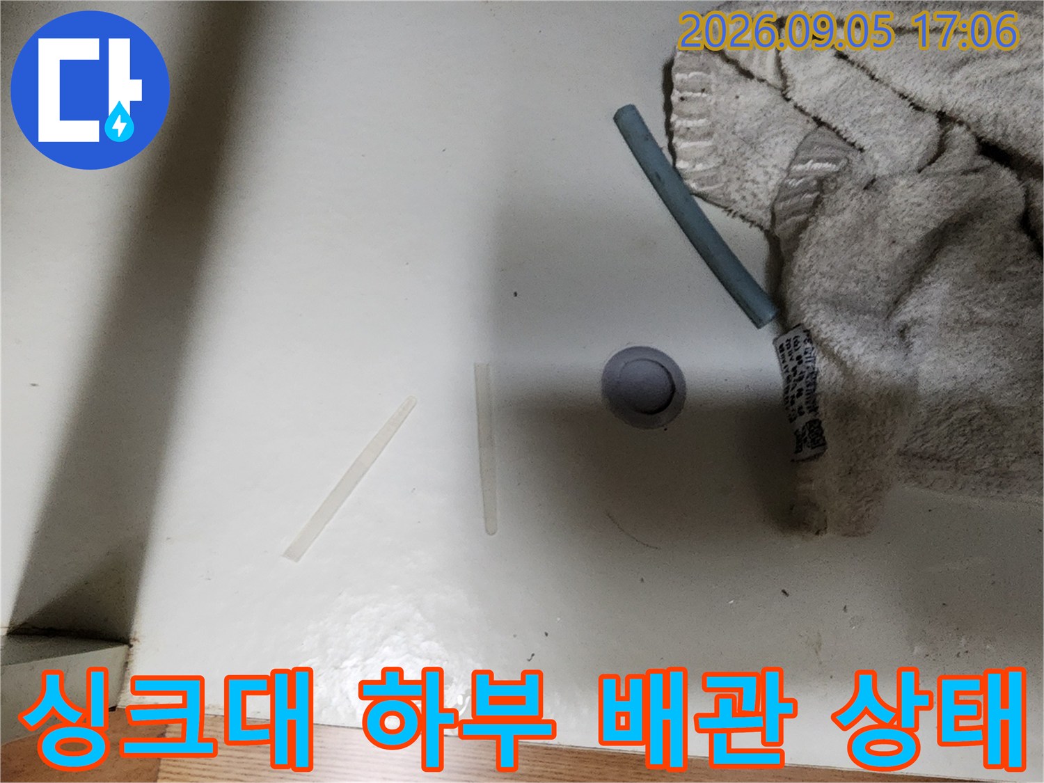 성남동 싱크대 하부장 내부의 배관 연결 부위와 바닥 상태를 보여주는 사진입니다.