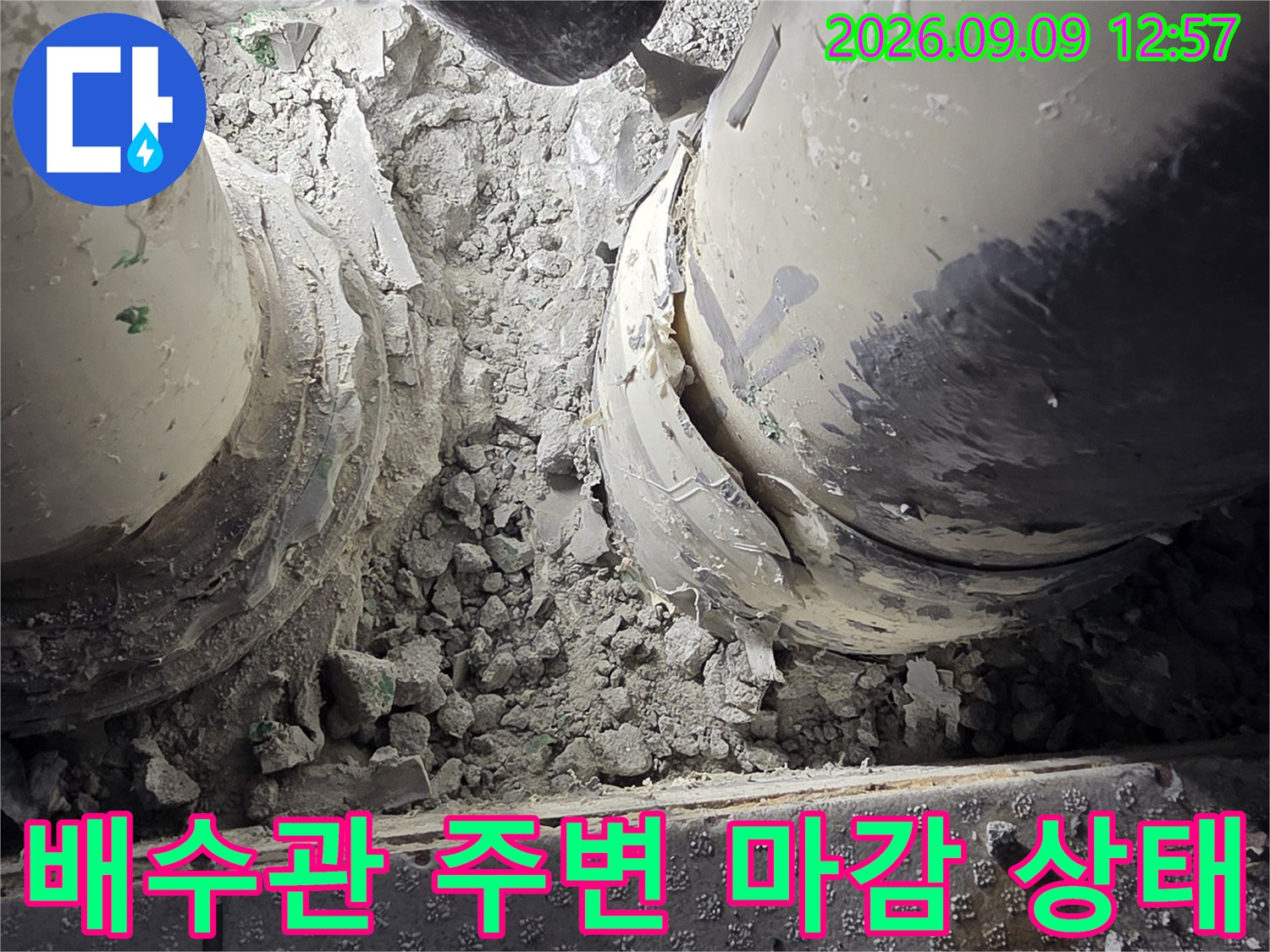 다용도실 배수관 연결부의 파손된 마감재를 보여줍니다.