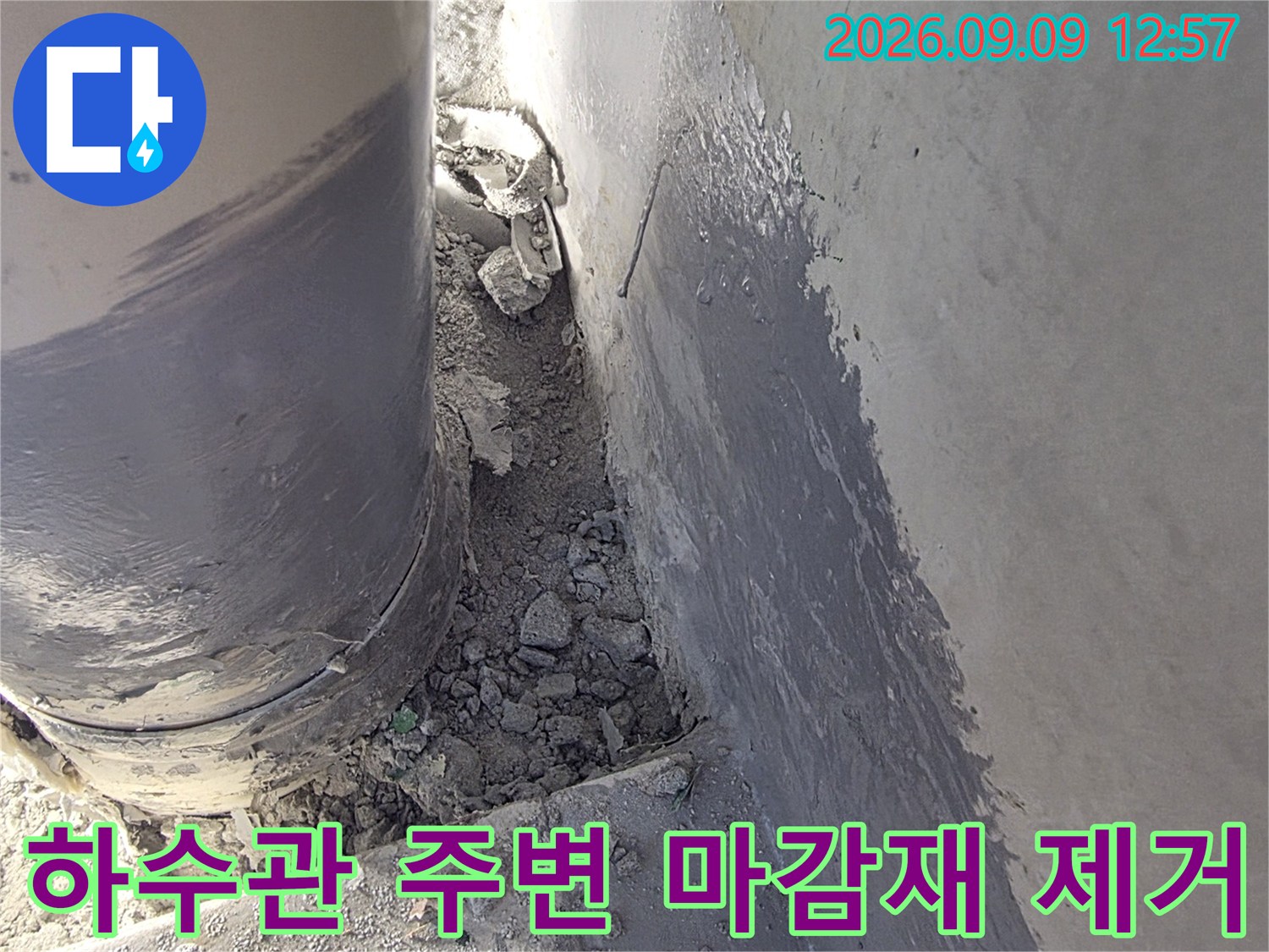 배수관 주변의 부서진 시멘트와 노출된 배관 연결부