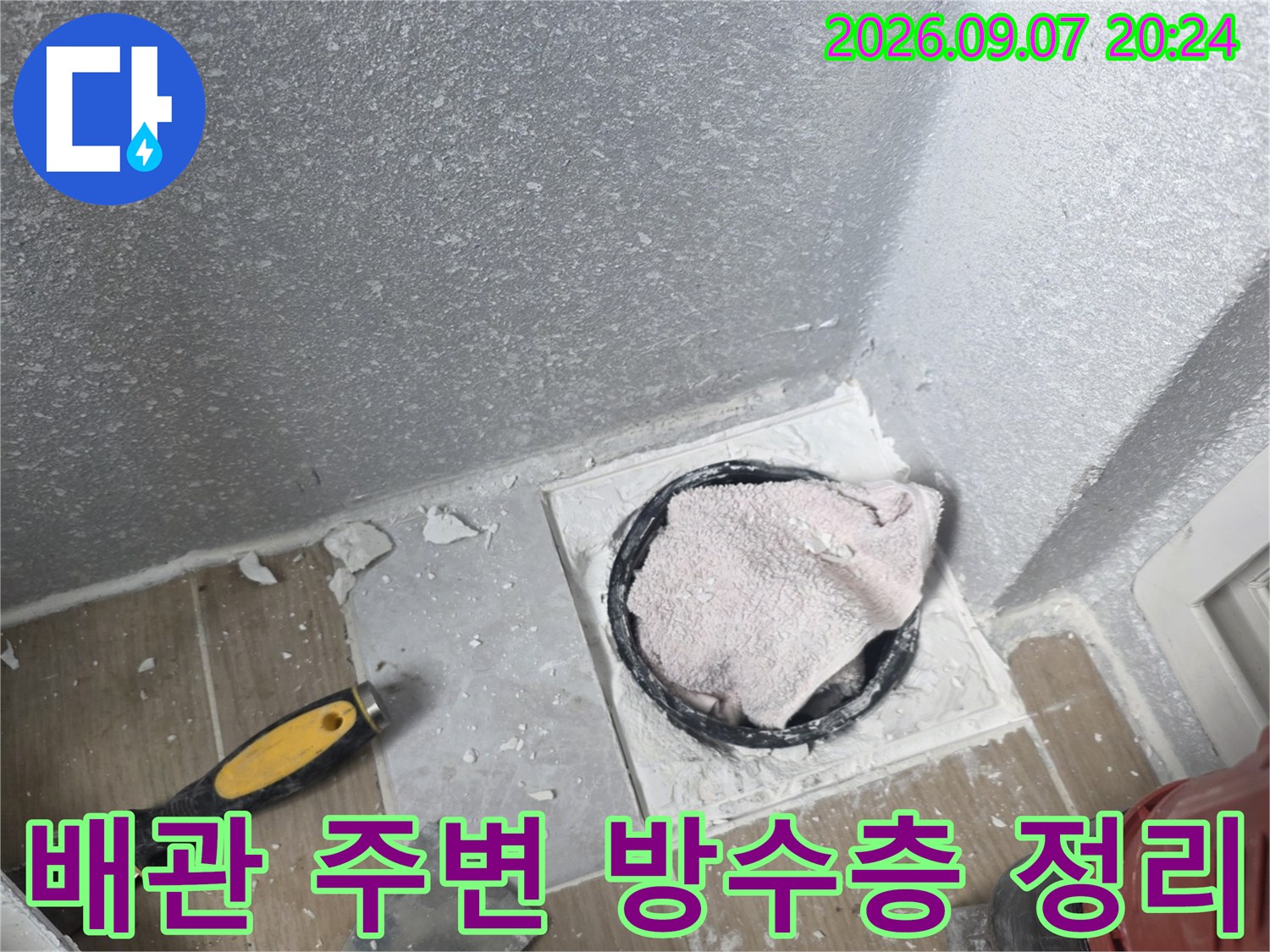 배수관 주위의 낡은 충진재를 제거하고 배관 연결부를 노출시킨 작업 현장입니다.