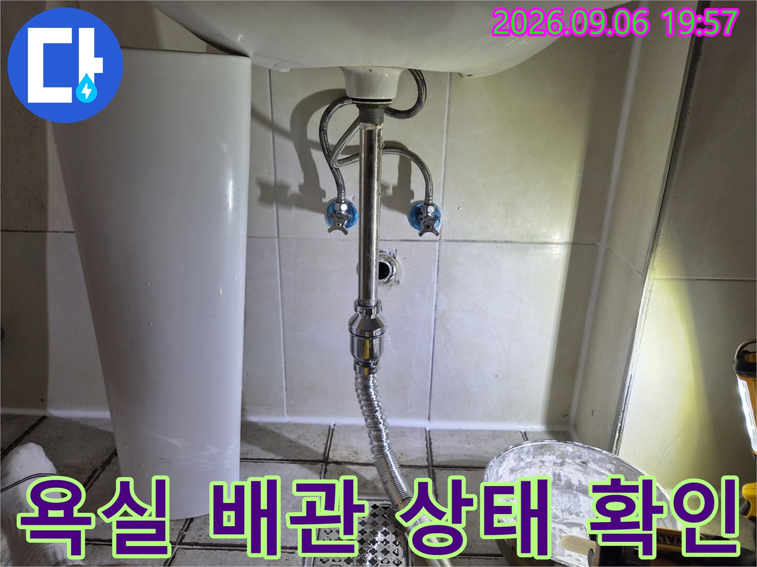세면대 아래쪽 은색 배관과 벽면 수전 밸브를 촬영한 사진입니다.