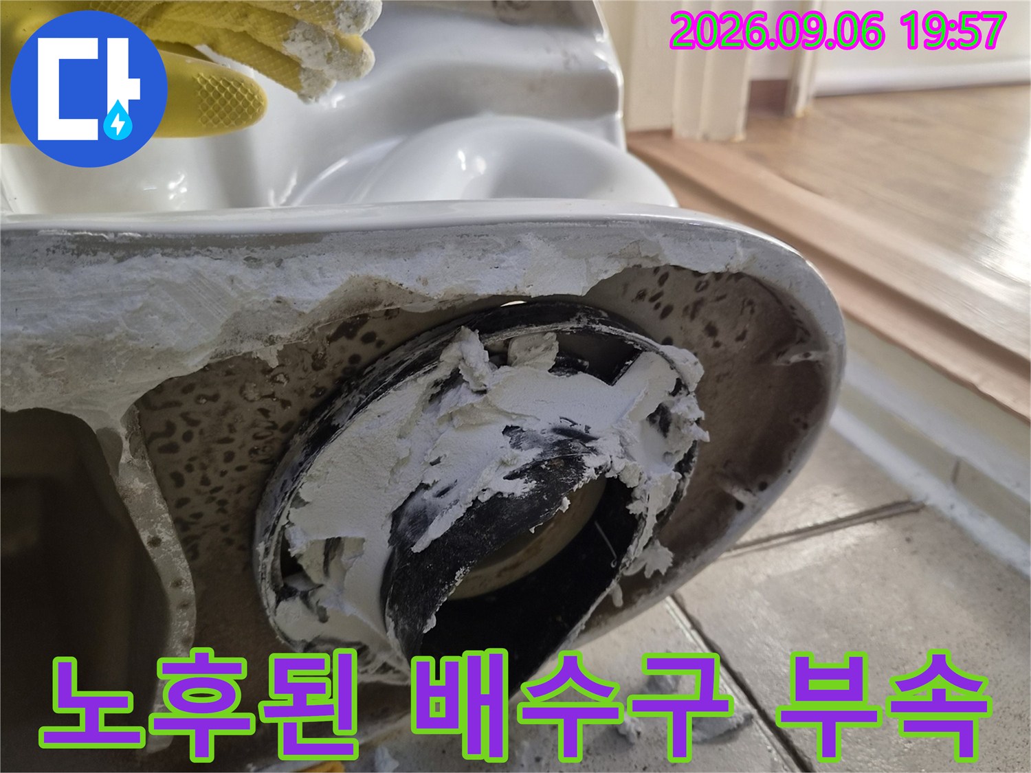 세면대 하부의 노후된 검은색 배수 부속과 주변에 묻은 백시멘트 잔해물