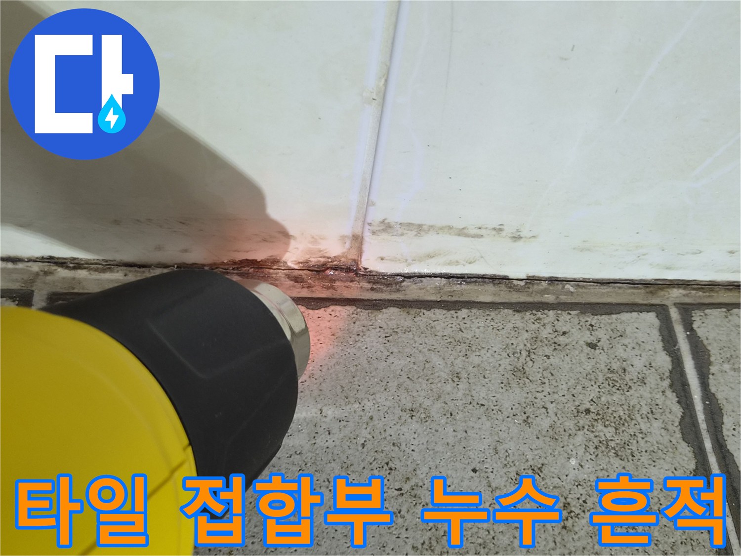 손전등 불빛으로 비춘 타일 하단부의 균열과 습기 상태