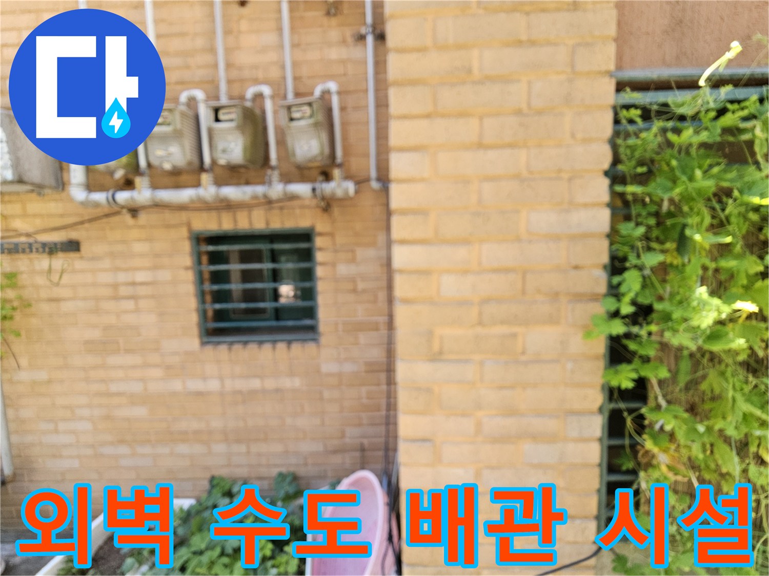 건물 외벽 벽돌 구조물에 설치된 다수의 수도 계량기와 공급 배관입니다.
