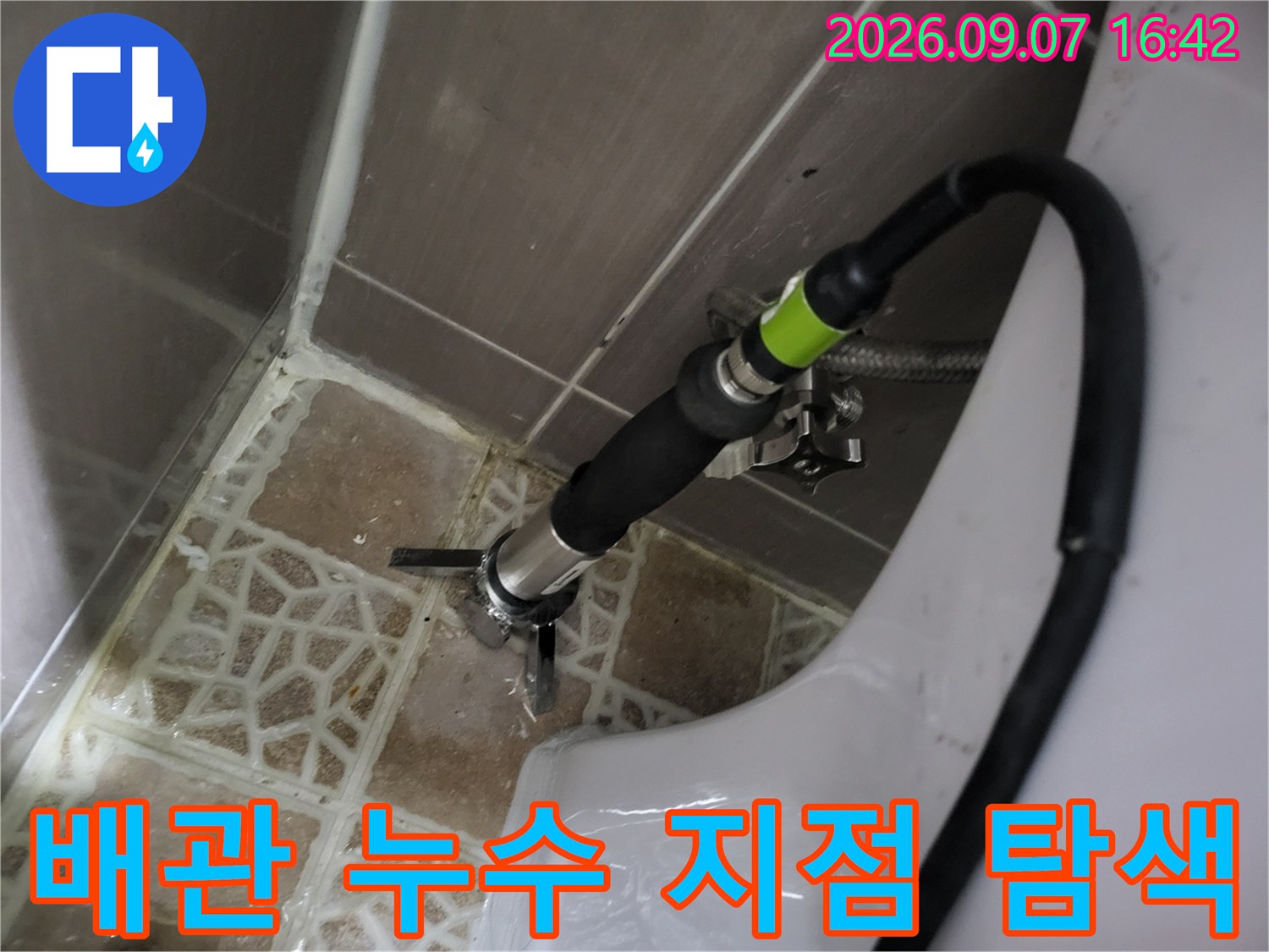 변기 주변 타일 배관 부위에 장비를 연결하여 점검하는 모습입니다.